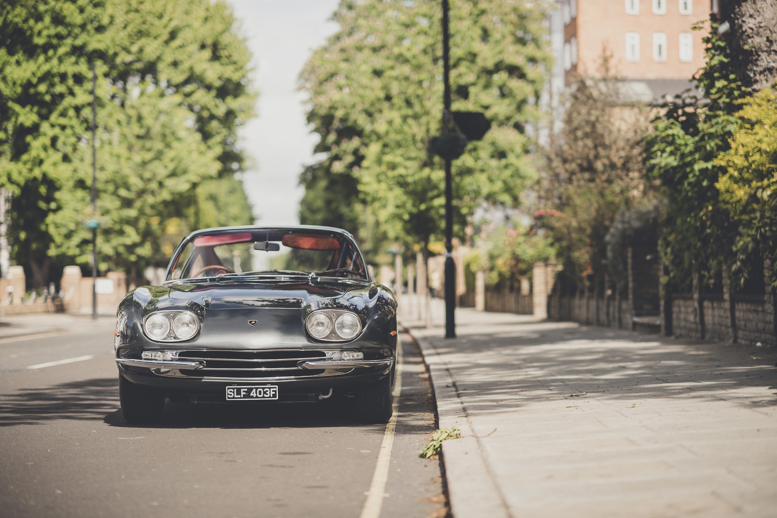 Lamborghini Celebrates The Beatles' Legacy With A 400 Gt 2+2 London Tour 11 Dark green lamborghini 400 gt 2+2 viewed from the front on a london street with trees and buildings in the background