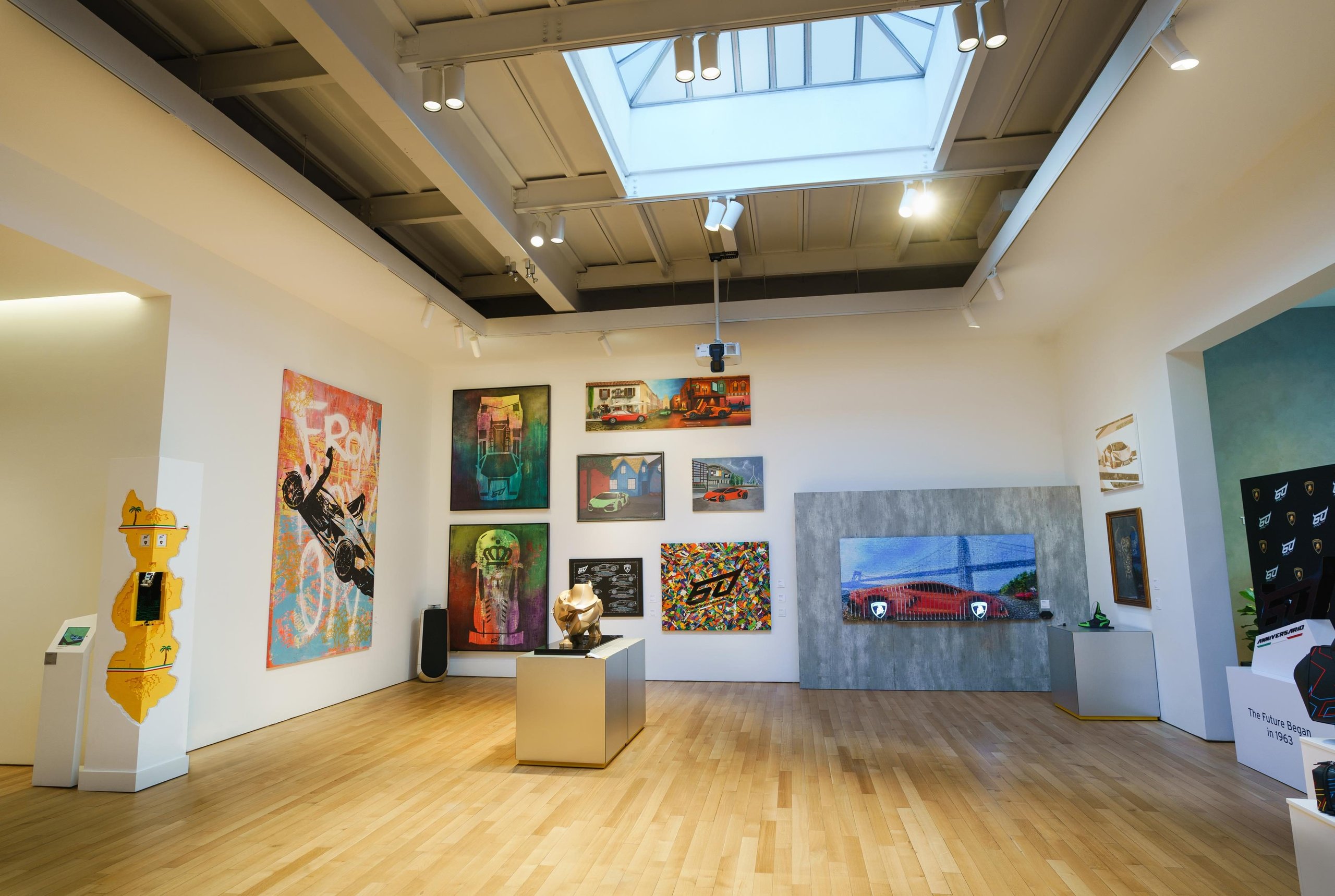 Why Lamborghini Opened Its Private Nyc Lounge To The Public For The First Time 3 Wide view of the lamborghini 60th anniversary art exhibition with colorful paintings and sculptures under a skylight