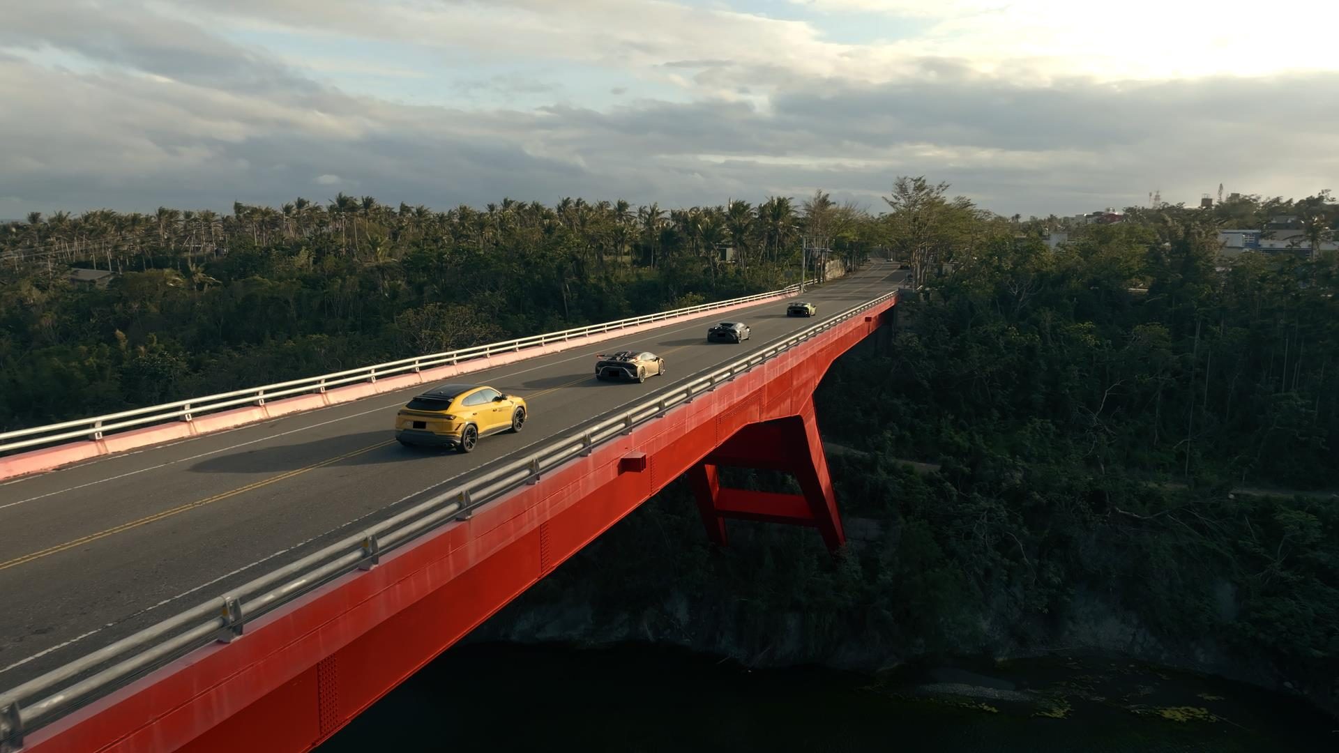 Seventy Lamborghinis, One Kinetic Sculpture, And Taiwan'S Eastern Coast: Inside The 60Th Anniversary Esperienza Giro 9 Aerial view of a lamborghini convoy including a yellow urus and huracáns crossing a long red bridge surrounded by lush green landscapes