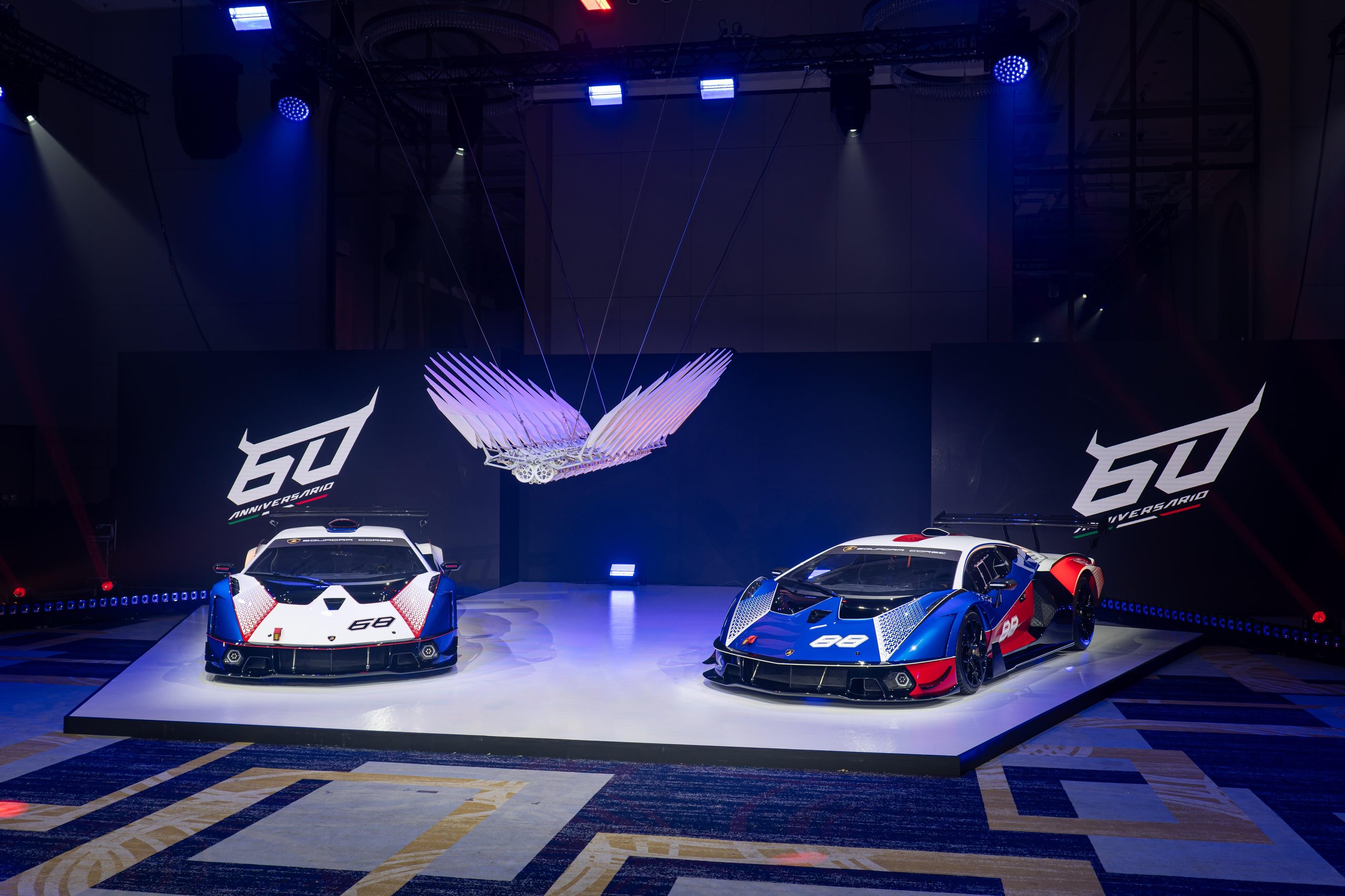 Two lamborghini essenza scv12 hypercars displayed on stage beneath the ll60 kinetic sculpture at the 60th anniversary gala in taipei