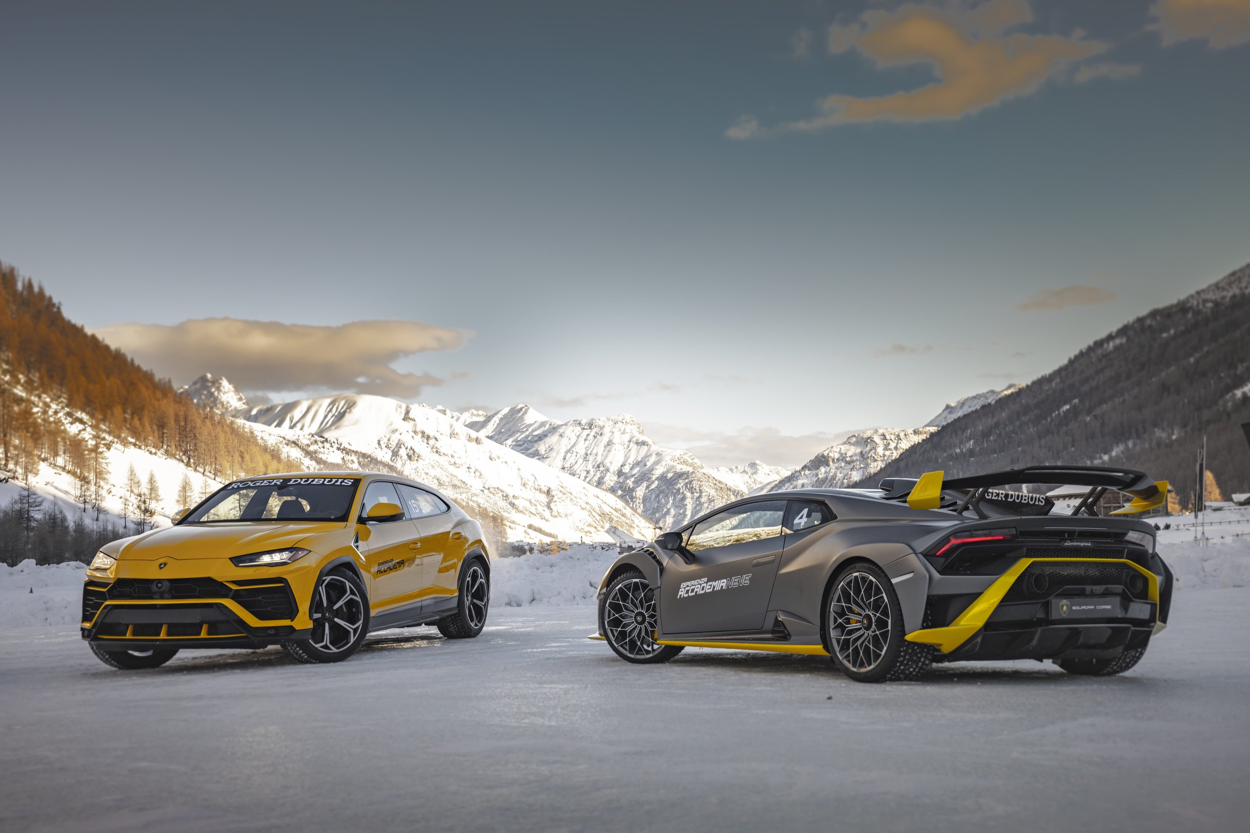 Accademia Neve 2022: What Lamborghini'S Ice Driving Program Actually Teaches Owners About Their Cars 15 Yellow lamborghini urus and matte grey huracán sto parked side by side on snow with snow-capped mountains under dramatic sky at accademia neve 2022