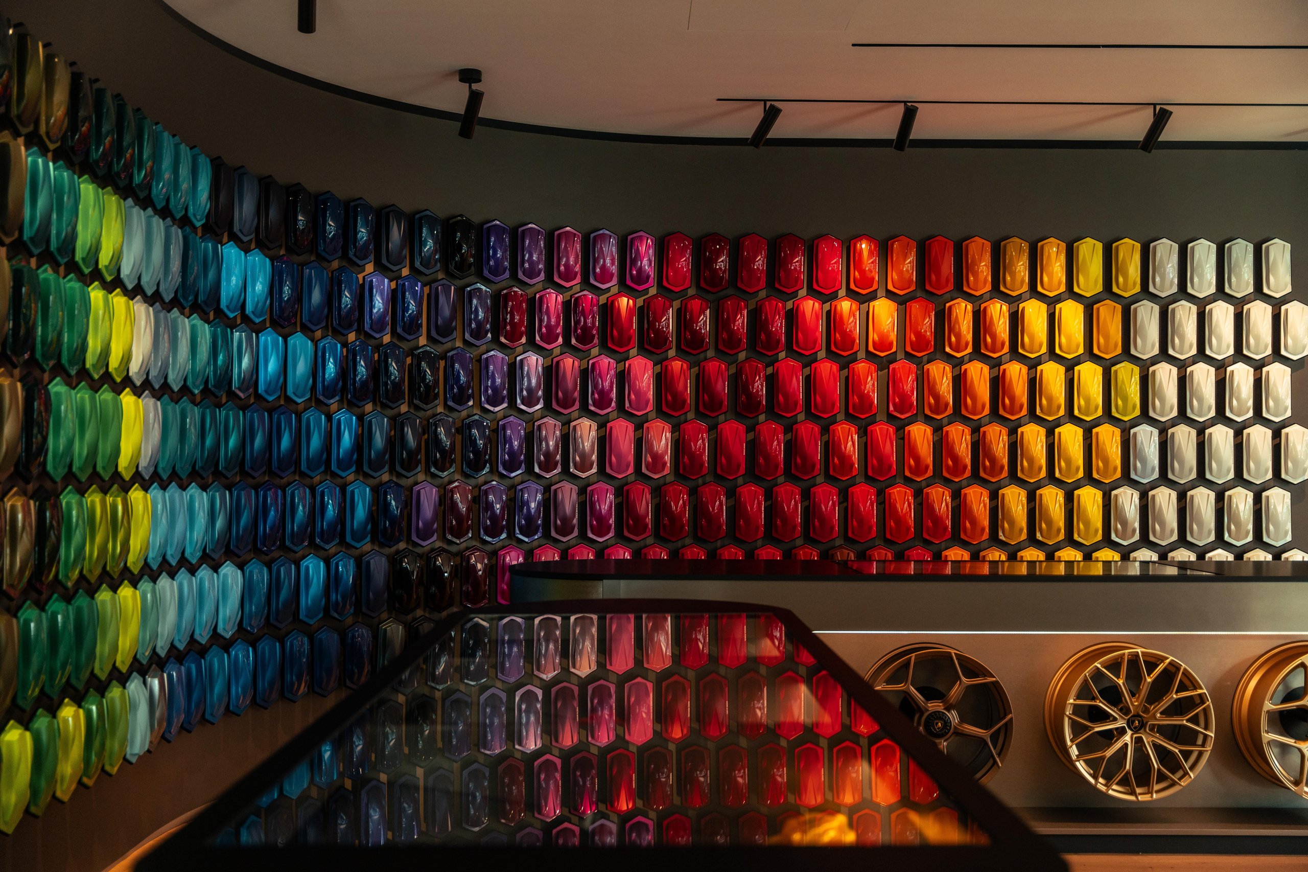 Close-up of the ad personam studio's paint sample wall showing a vibrant spectrum from blues and greens to reds and yellows