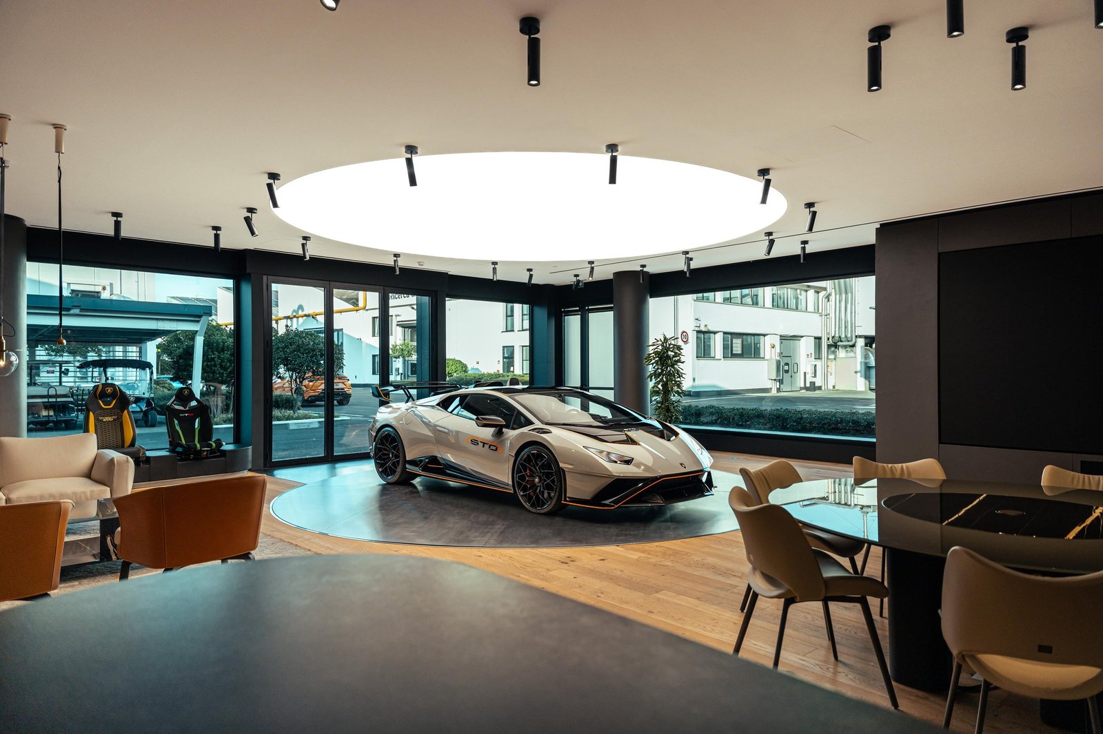 White Lamborghini Huracán STO with orange accents on a revolving platform inside the redesigned Ad Personam Studio