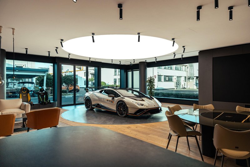 White Lamborghini Huracán STO with orange accents on a revolving platform inside the redesigned Ad Personam Studio