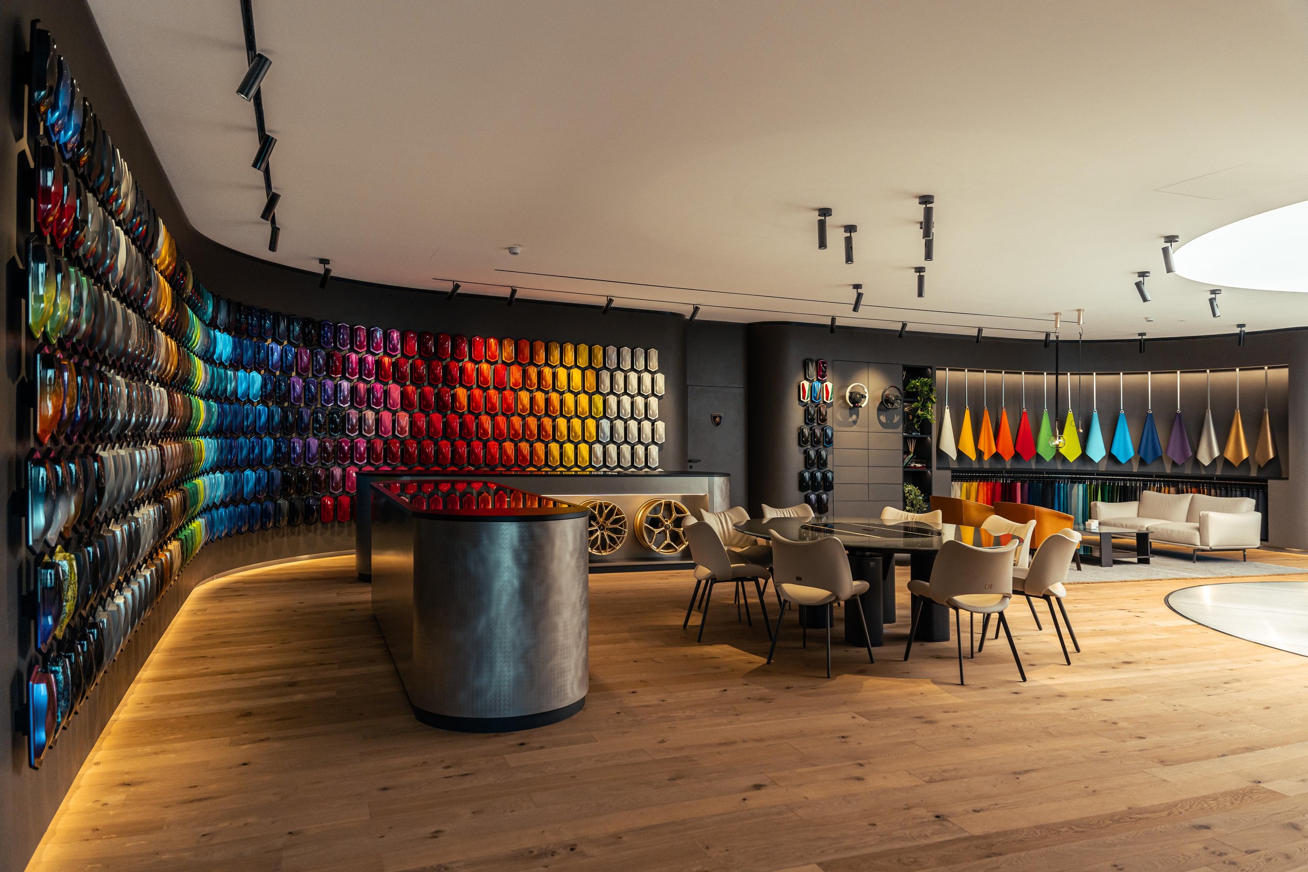 Wide shot of the redesigned ad personam studio showing curved paint sample wall, consultation table, and lounge area with fabric displays
