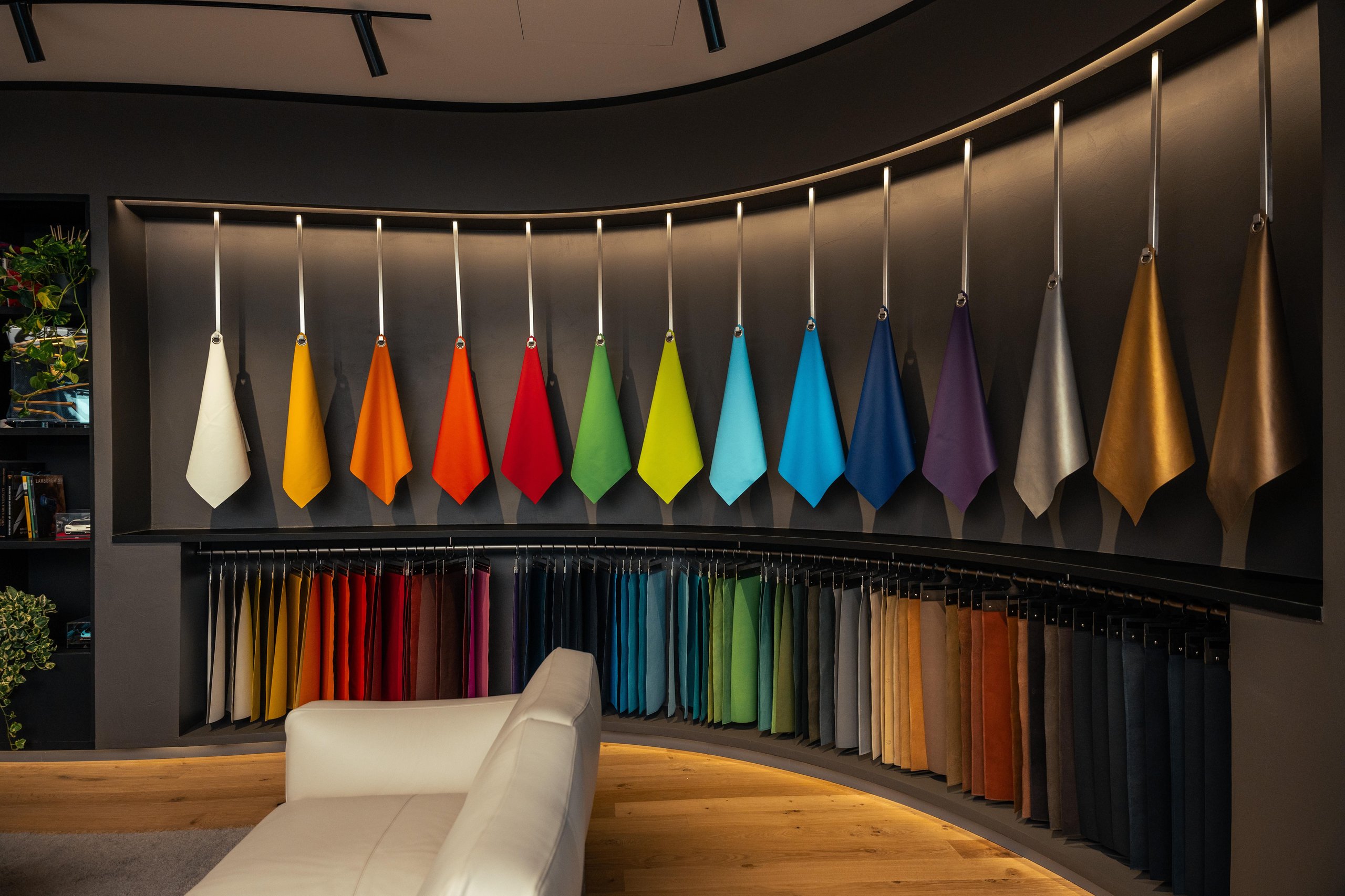 Curved display of hanging fabric and leather samples in various colors inside the ad personam studio lounge area