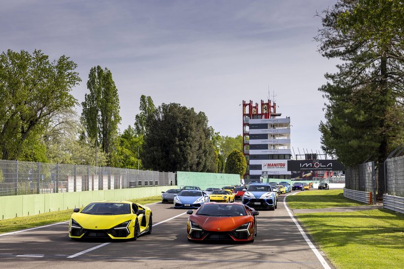 A procession of Lamborghini Revuelto, Huracán, and Urus models driving on the Imola Circuit during the Lamborghini Arena event