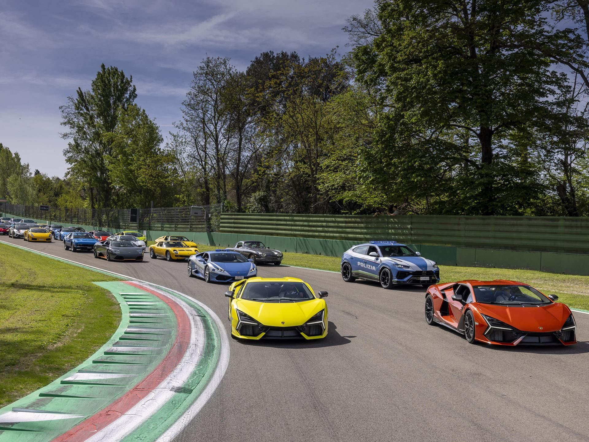 Lamborghini Arena 2026 Returns To Imola With Super Trofeo Racing, Miura Anniversary, And A Bigger Playbook 5 A convoy of lamborghini models including a yellow revuelto, orange revuelto, and blue urus on the imola race track