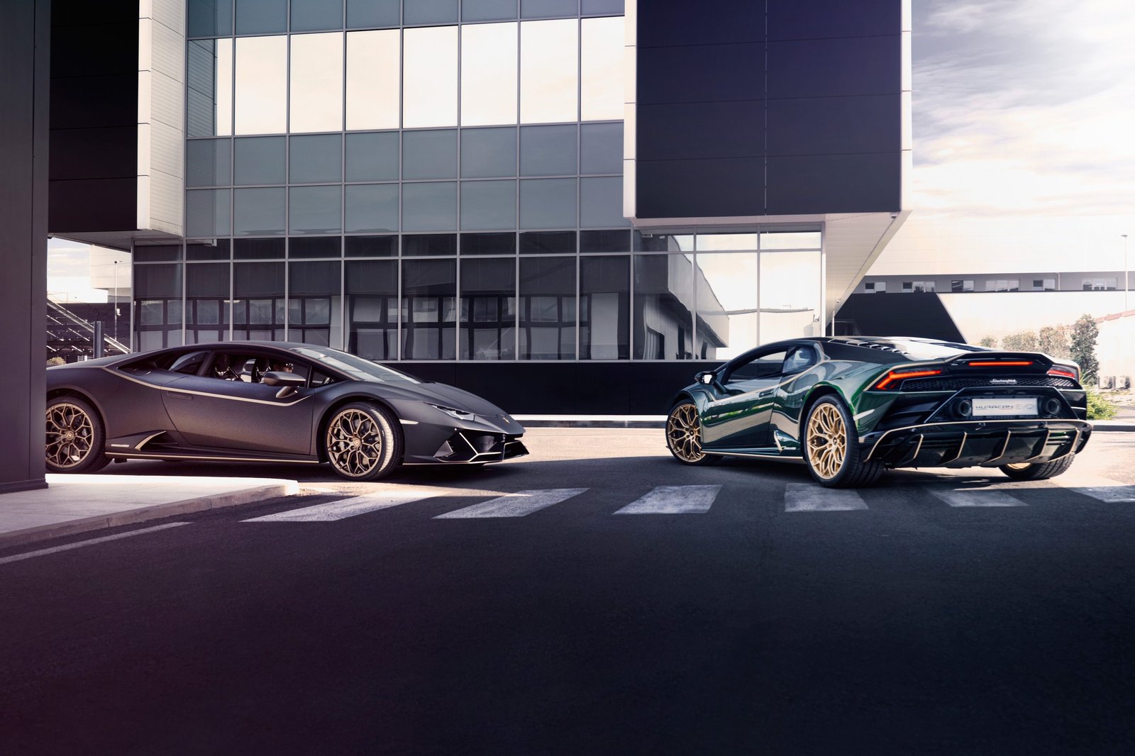 A matte grey Lamborghini Huracán STO and a green Huracán EVO parked facing opposite directions on a crosswalk, illustrating the range of Lamborghini's award-winning V10 lineup