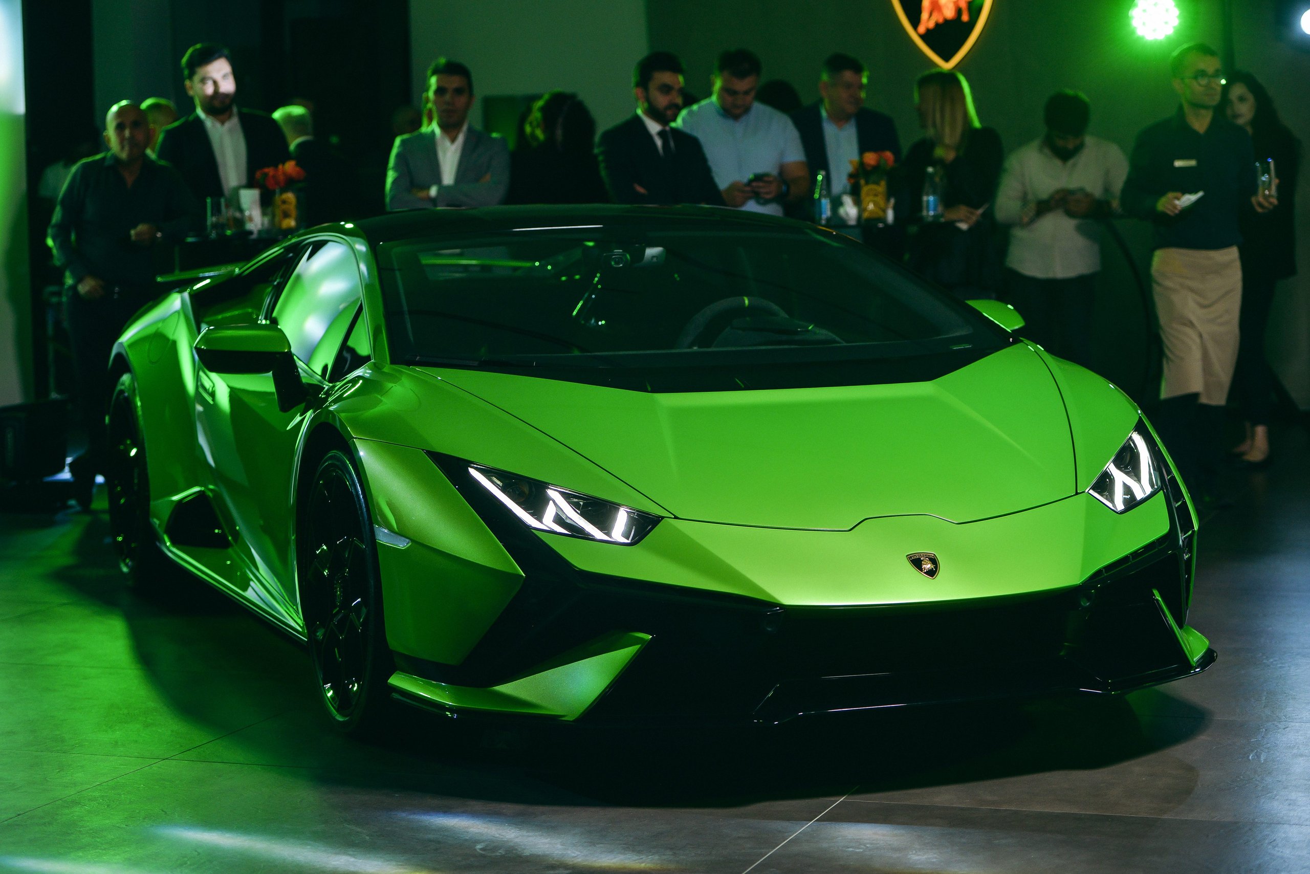 Lamborghini Baku: Why A 225 Square Meter Showroom Signals Serious Ambitions For The Transcaucasia Region 7 A vibrant green lamborghini huracán evo showcased under green lighting at the baku launch event with attendees in the background