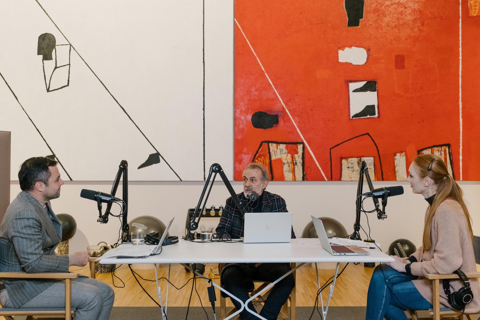Massimo Bottura and podcast hosts recording an episode of Beyond: A Lamborghini Podcast, seated at a table with microphones and abstract art behind them