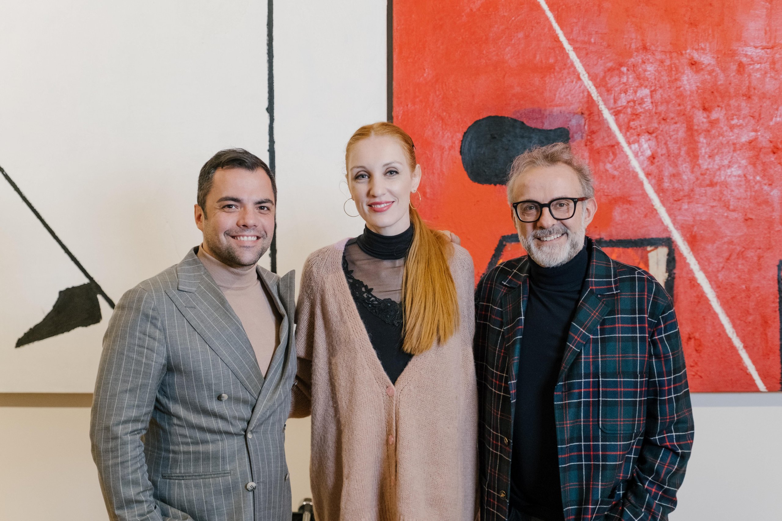 Why Lamborghini Put A Revuelto On A Serving Tray: The 'Beyond' Podcast'S Bottura Episode And The Brand Strategy Behind It 7 Three individuals smiling in front of a large abstract painting with red and white elements