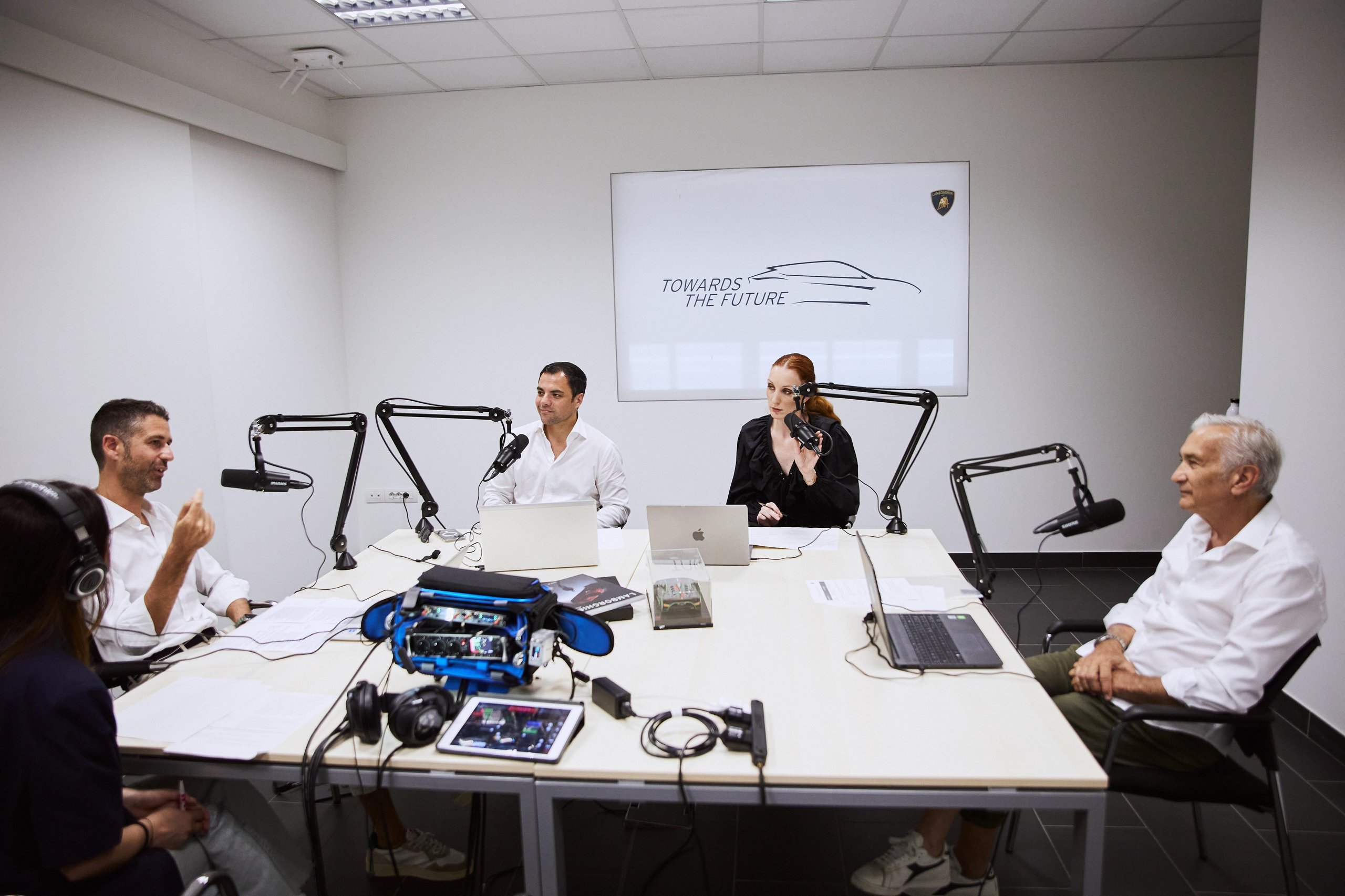 Inside Lamborghini'S 'Beyond' Podcast: How The Revuelto'S Product Director And Ducati'S Motogp Boss Define Winning Culture 9 Four people seated around a table recording the beyond podcast, with microphones, laptops, and a towards the future graphic on the wall