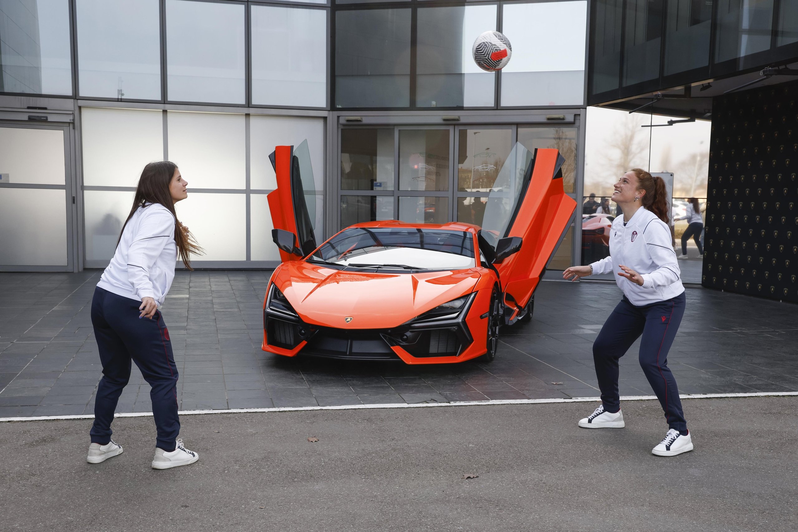 Lamborghini Brings Bologna'S Women'S Football Team To Sant'Agata, Signaling A Broader Brand Play 3 Two bologna fc femminile players juggle a football in front of an orange lamborghini revuelto with scissor doors open