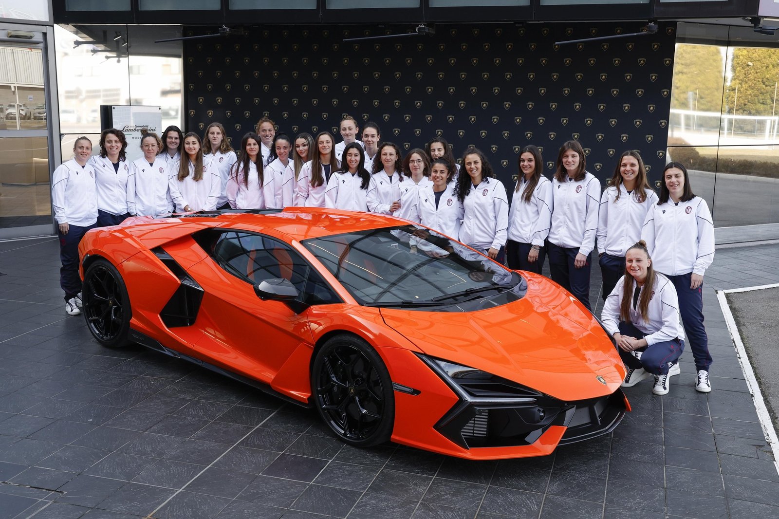 Bologna FC 1909 Femminile players pose with an orange Lamborghini Revuelto outside the Lamborghini headquarters in Sant'Agata Bolognese