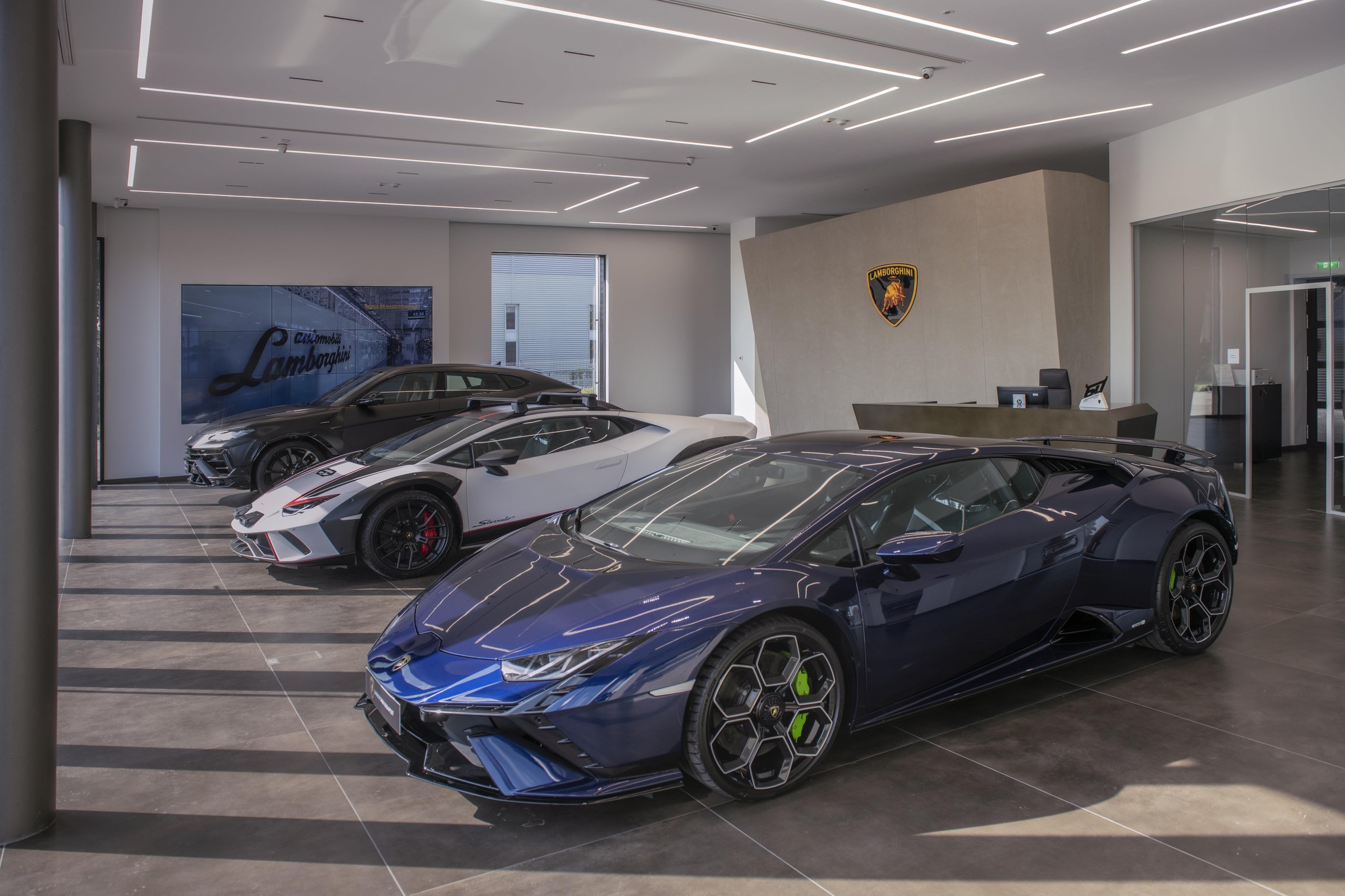 Budapest Gets Its First Lamborghini Showroom, And The Revuelto Came Along To Make The Point 11 Three lamborghini vehicles on display in the budapest showroom: blue huracán tecnica, white huracán sterrato, and dark urus