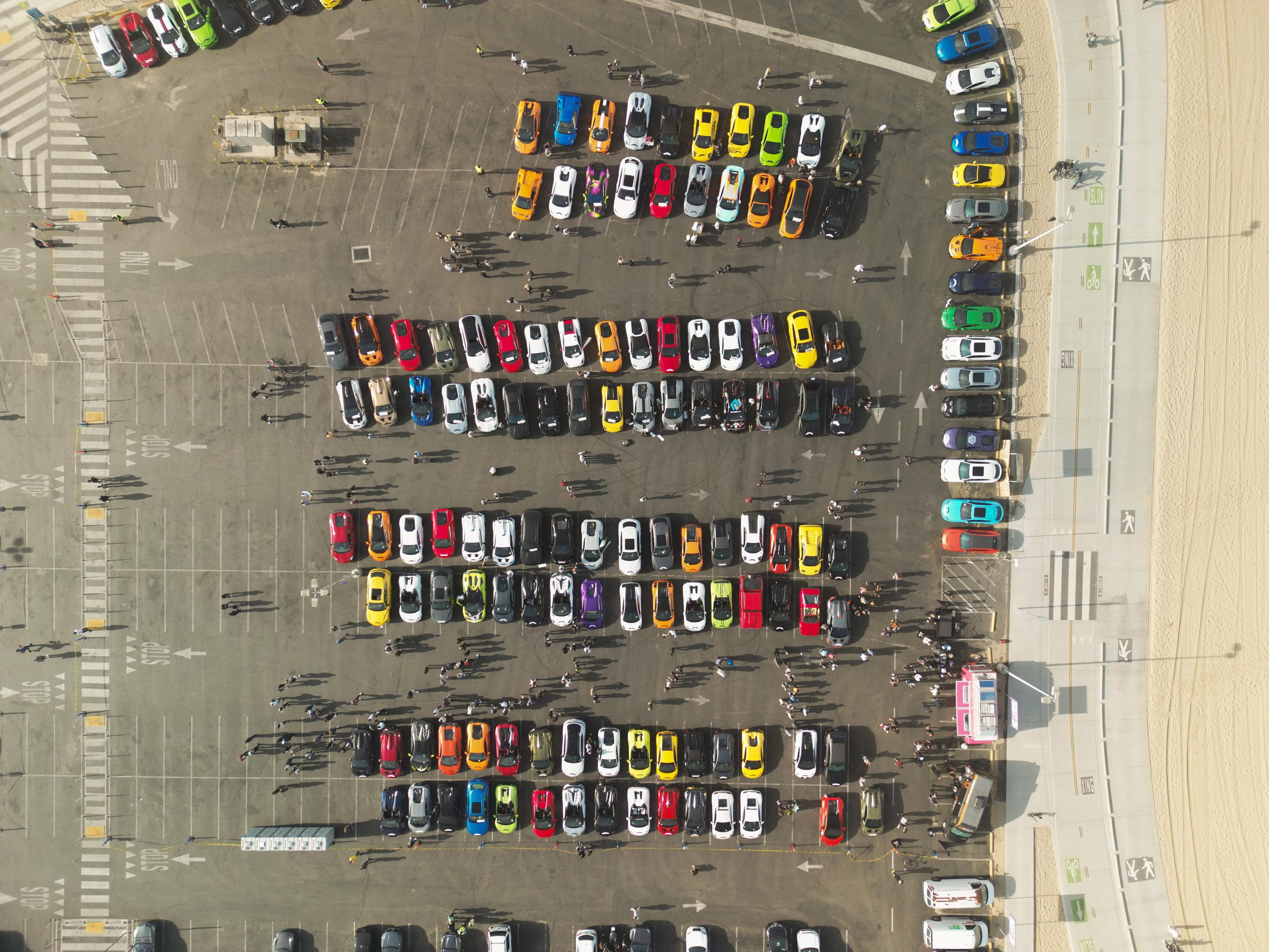 200 Mustache-Wearing Lamborghinis Took Over Malibu, And The Ceo Was Leading The Pack 3 Aerial top-down view of hundreds of colorful lamborghini supercars gathered in a parking lot adjacent to santa monica beach and the ocean
