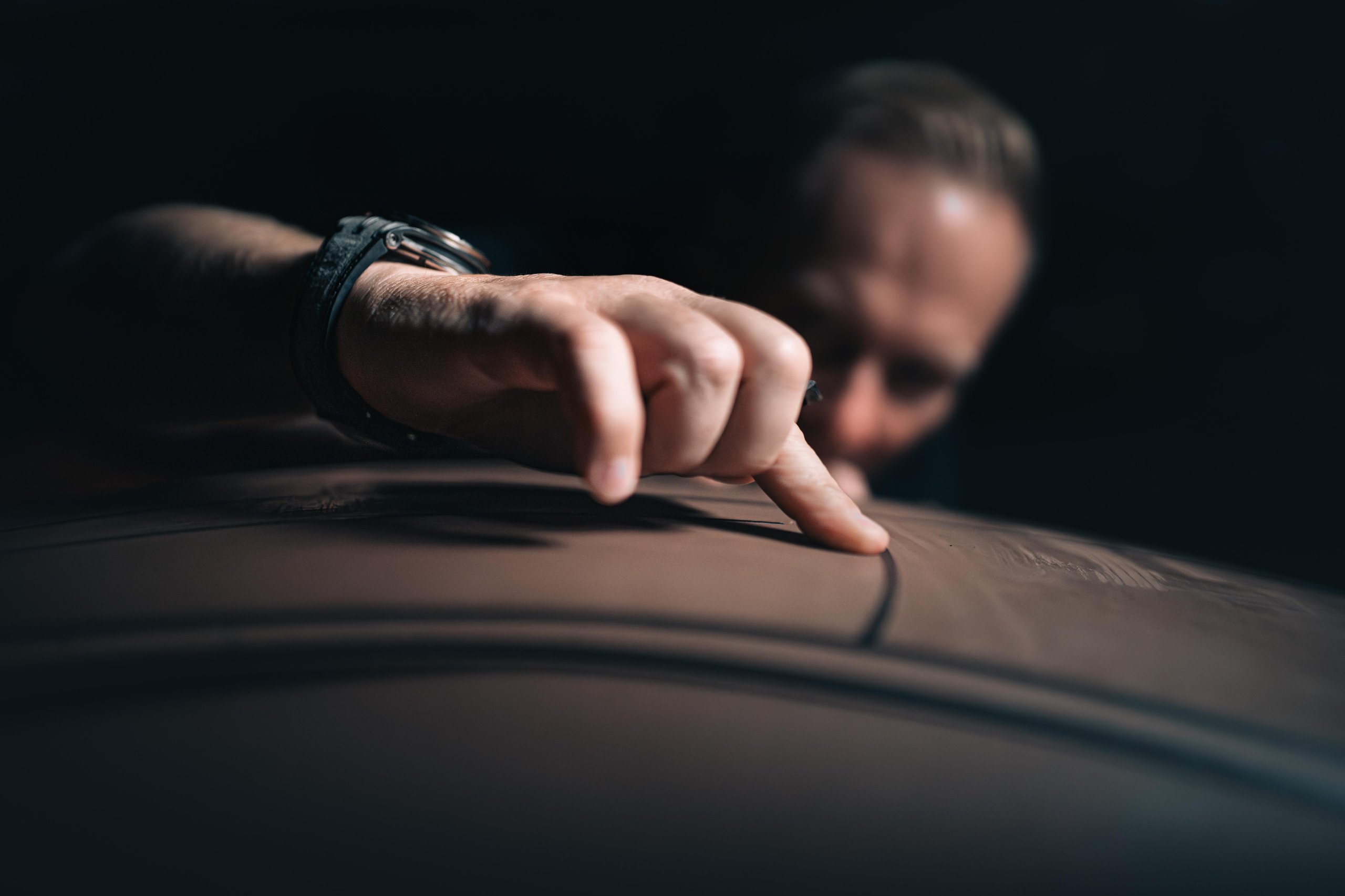 Close-up of a Lamborghini designer's hand meticulously tracing a line on a clay model surface