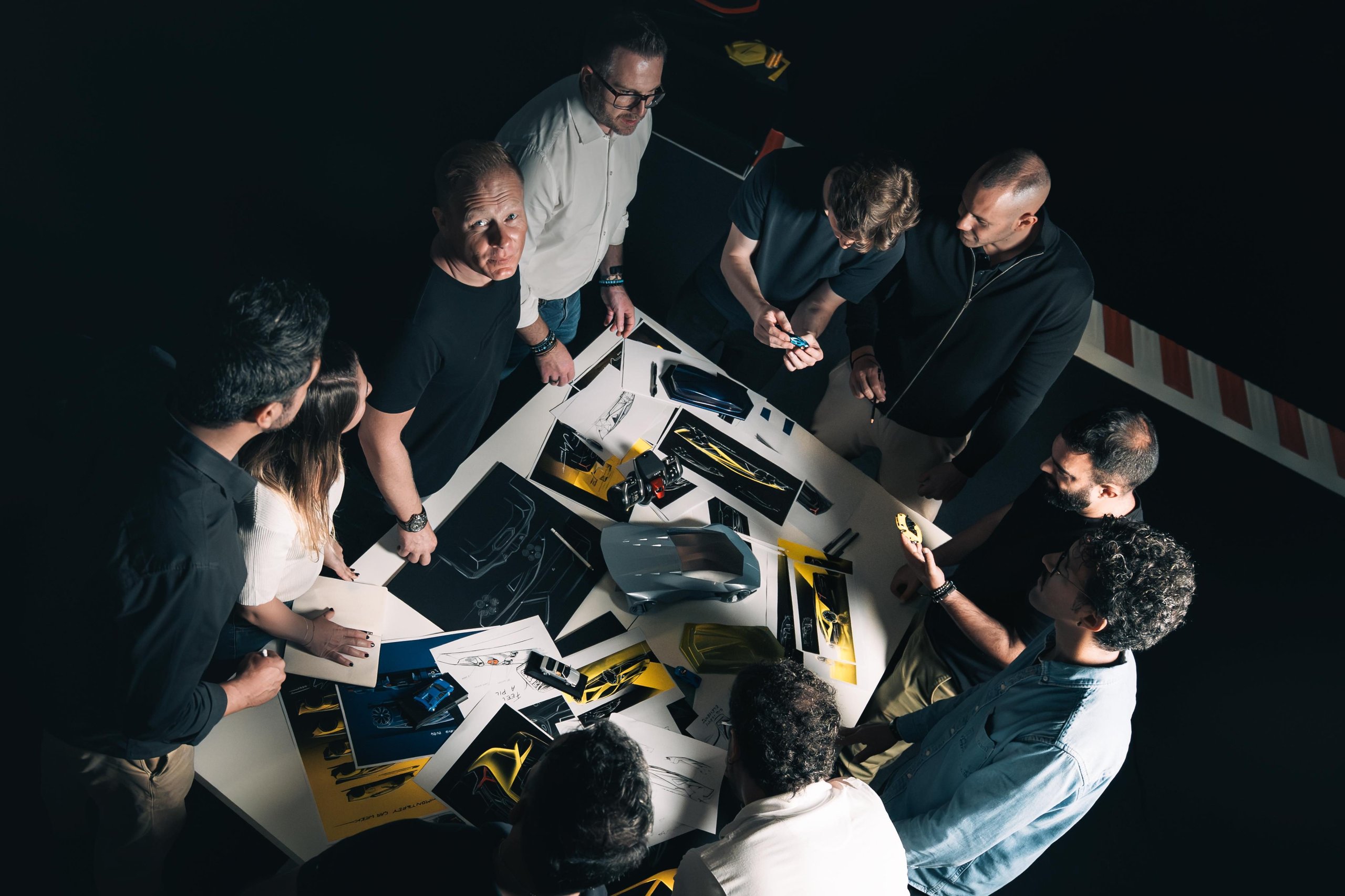 Lamborghini centro stile designers gathered around sketches and a futuristic concept car scale model