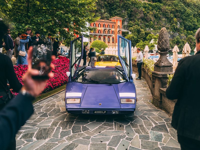 Purple Lamborghini Countach LP 400 with scissor doors open on a stone path surrounded by spectators at Villa d'Este