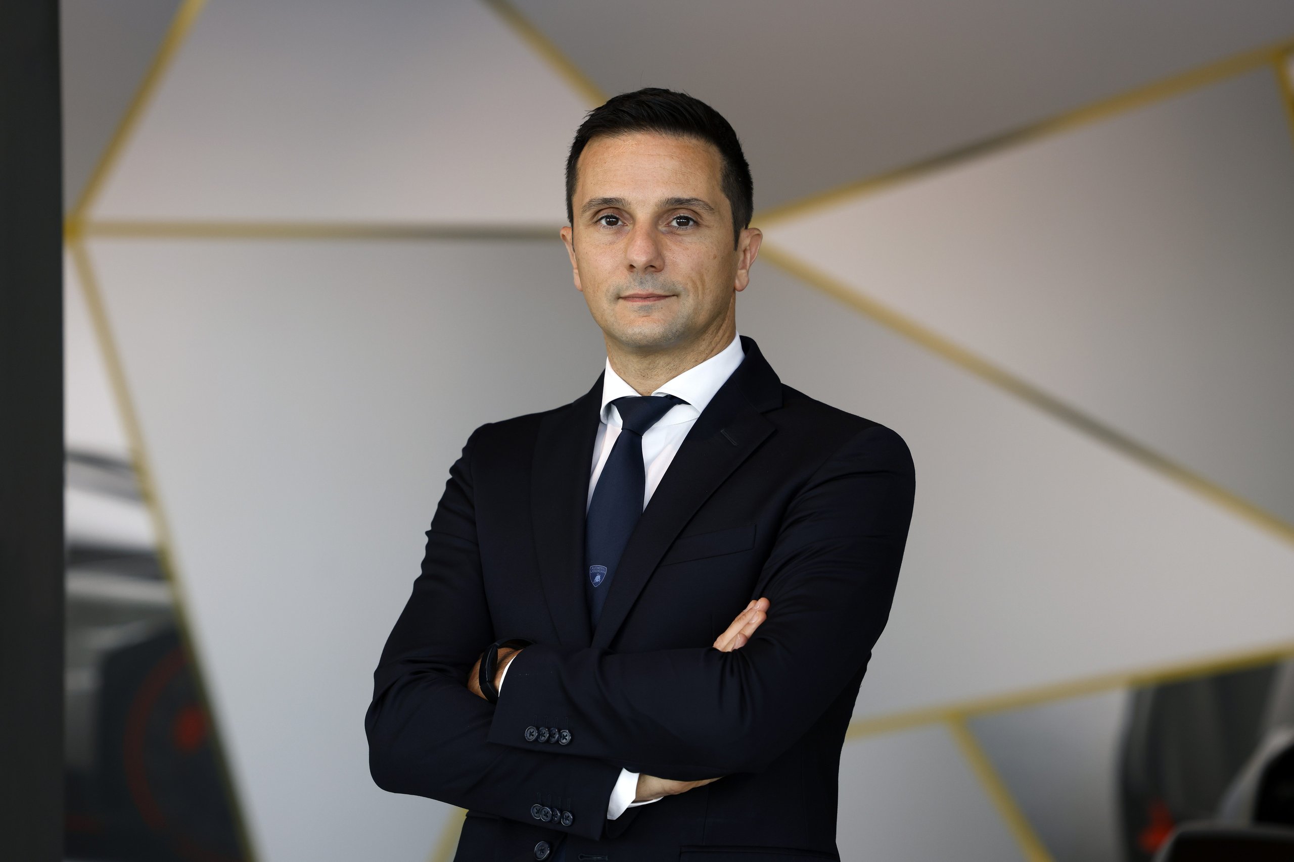 Paolo gabrielli, new chief procurement officer at automobili lamborghini, standing with arms crossed against a modern geometric background