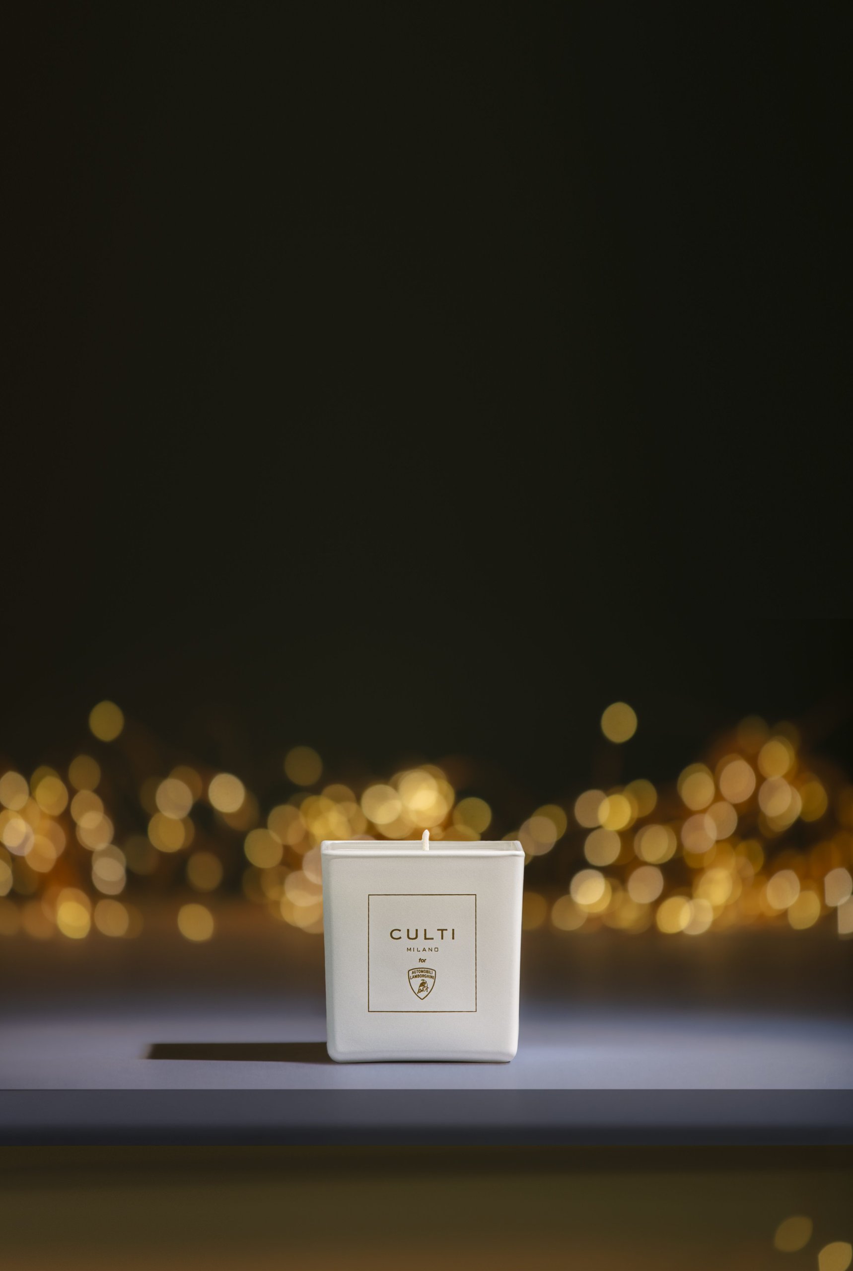 Lamborghini'S Scented Candle With Culti Milano Says More About Brand Strategy Than You'D Think 3 White culti milano for automobili lamborghini candle on dark surface with golden bokeh lights