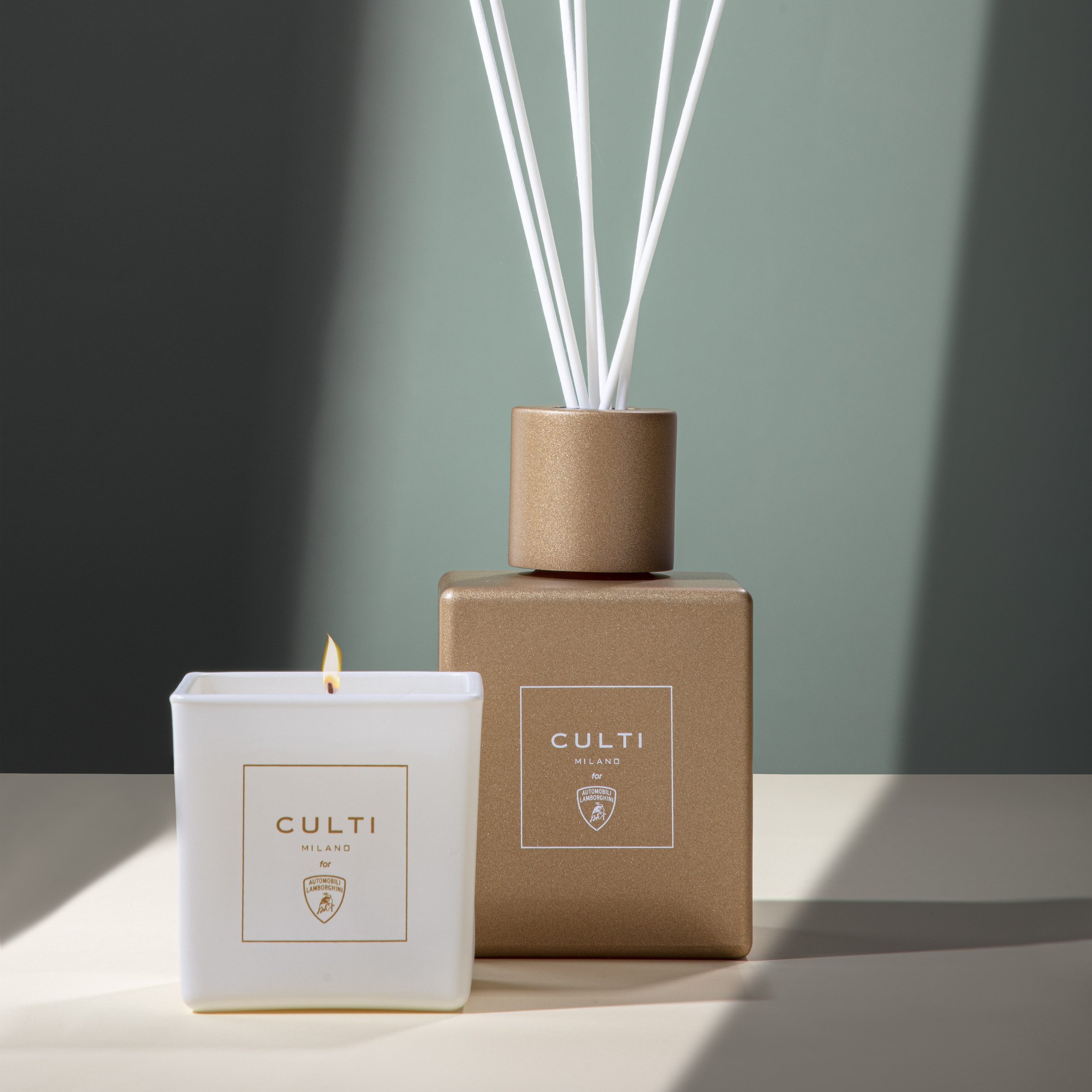 Lamborghini'S Scented Candle With Culti Milano Says More About Brand Strategy Than You'D Think 5 Lit lamborghini culti milano candle next to matte gold diffuser with white sticks against green-grey background