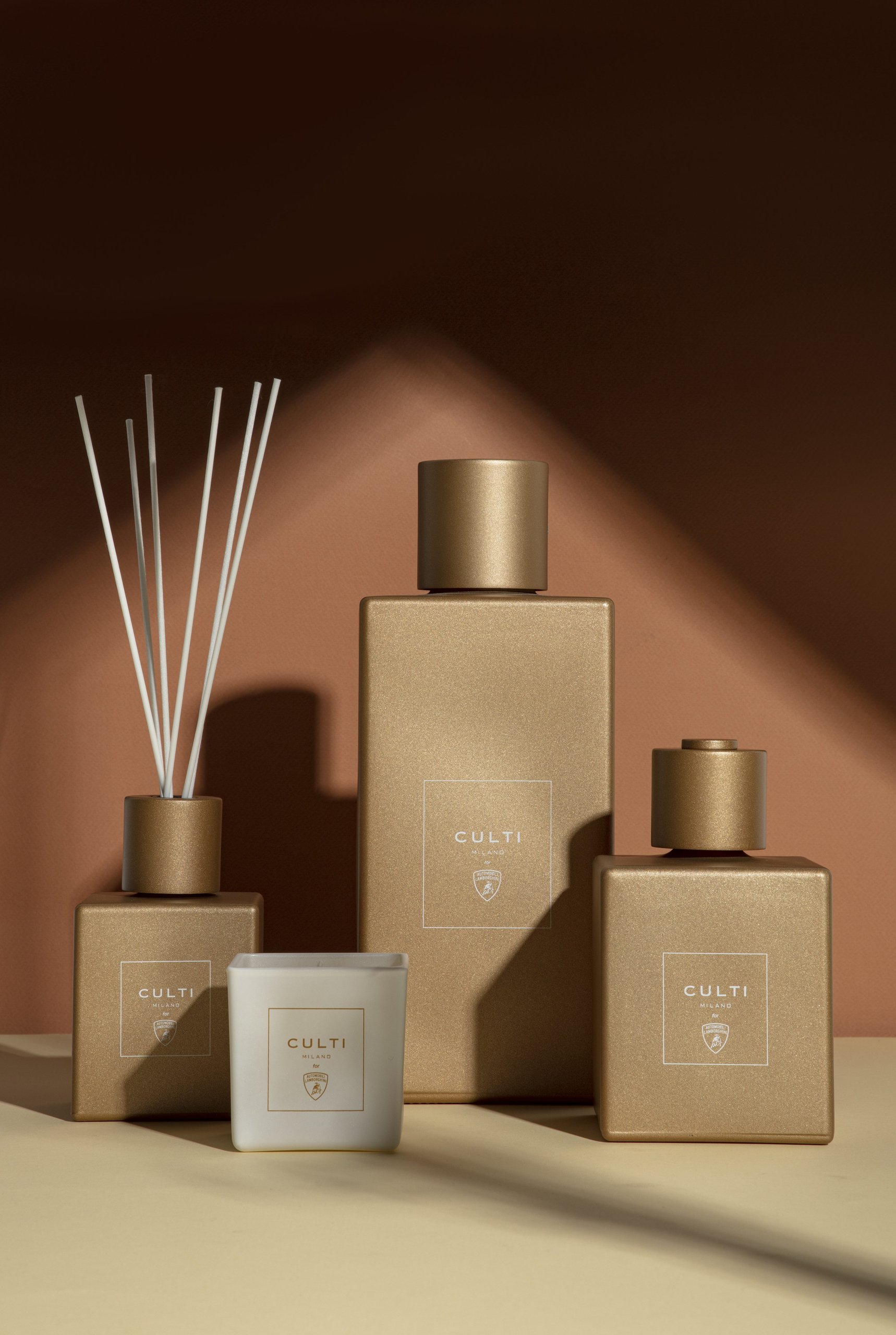 Lamborghini'S Scented Candle With Culti Milano Says More About Brand Strategy Than You'D Think 7 Close-up of unlit lamborghini culti milano candle with three matte gold diffusers on warm brown background