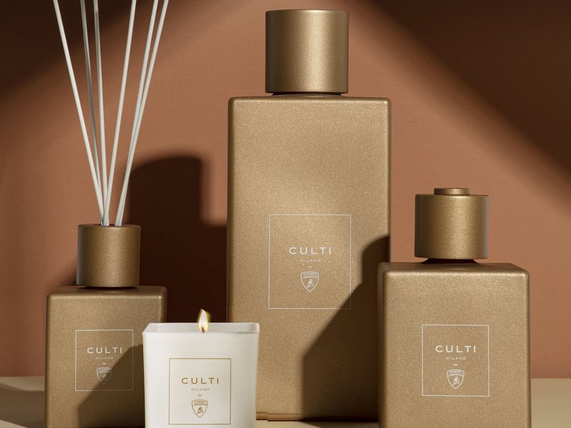 Culti Milano for Automobili Lamborghini home fragrance collection featuring a lit candle and three diffusers in matte gold finish