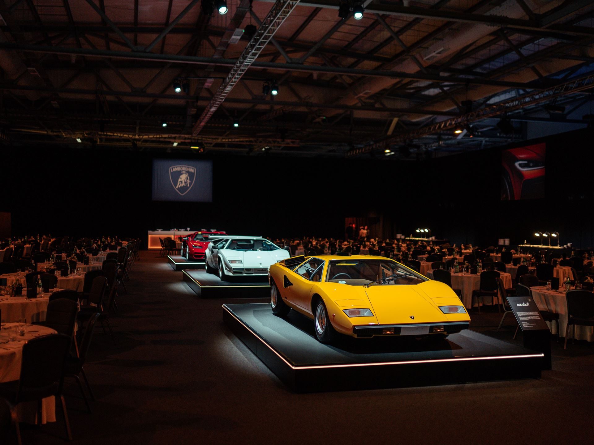 Multiple generations of lamborghini countach displayed together at an event, from the yellow lp400 to the red lpi 800-4