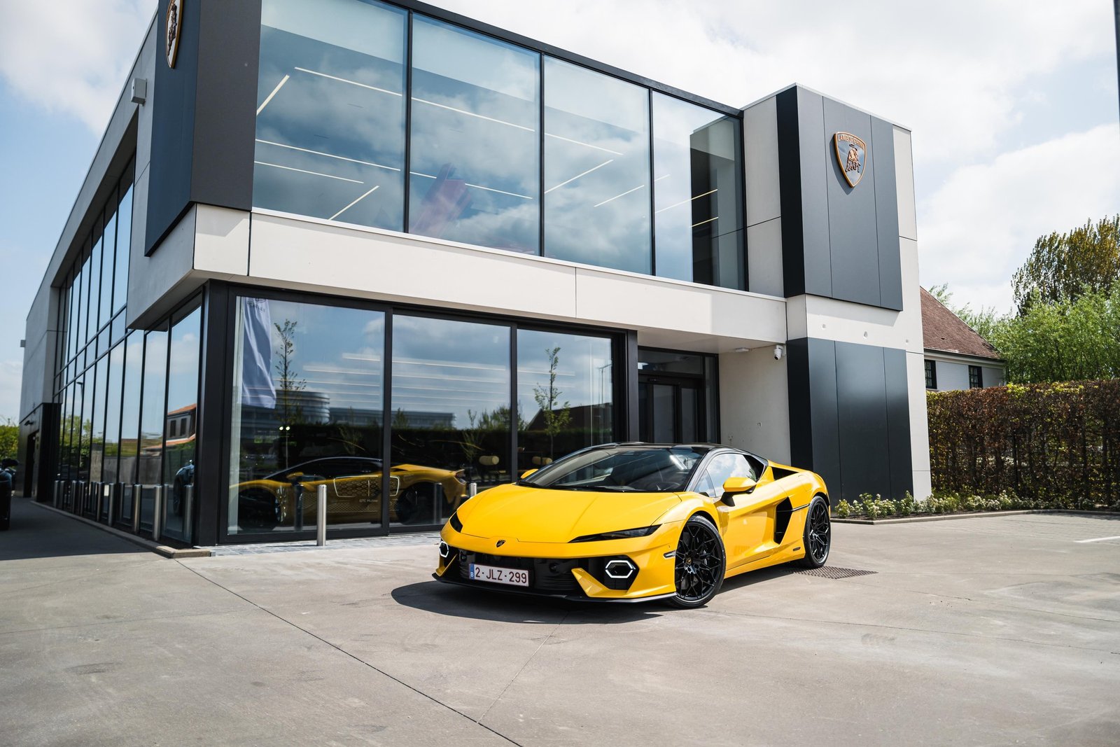 A bright yellow Lamborghini Temerario parked outside the new Lamborghini Knokke dealership with its modern glass facade
