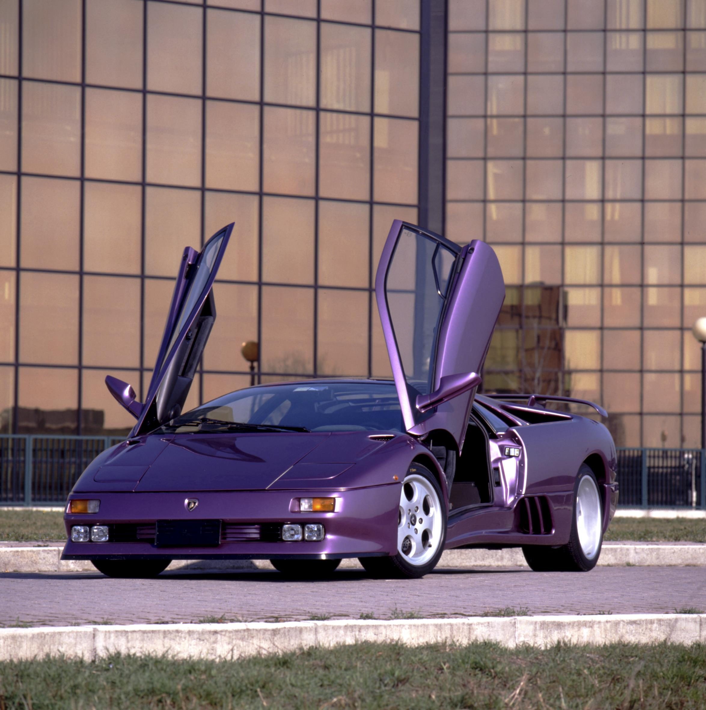 Lamborghini Diablo At 35: How The 1990S Speed King Built The Brand We Know Today 17 Purple lamborghini diablo with scissor doors open parked in front of a modern building with reflective glass windows