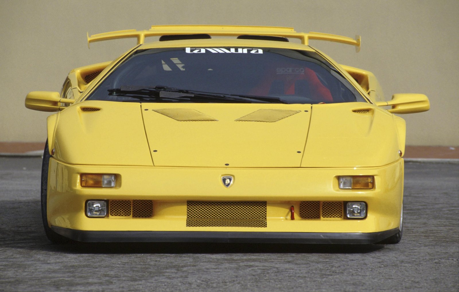 Head-on close-up of a yellow Lamborghini Diablo showing its aggressive front design, pop-up headlights, and prominent rear wing