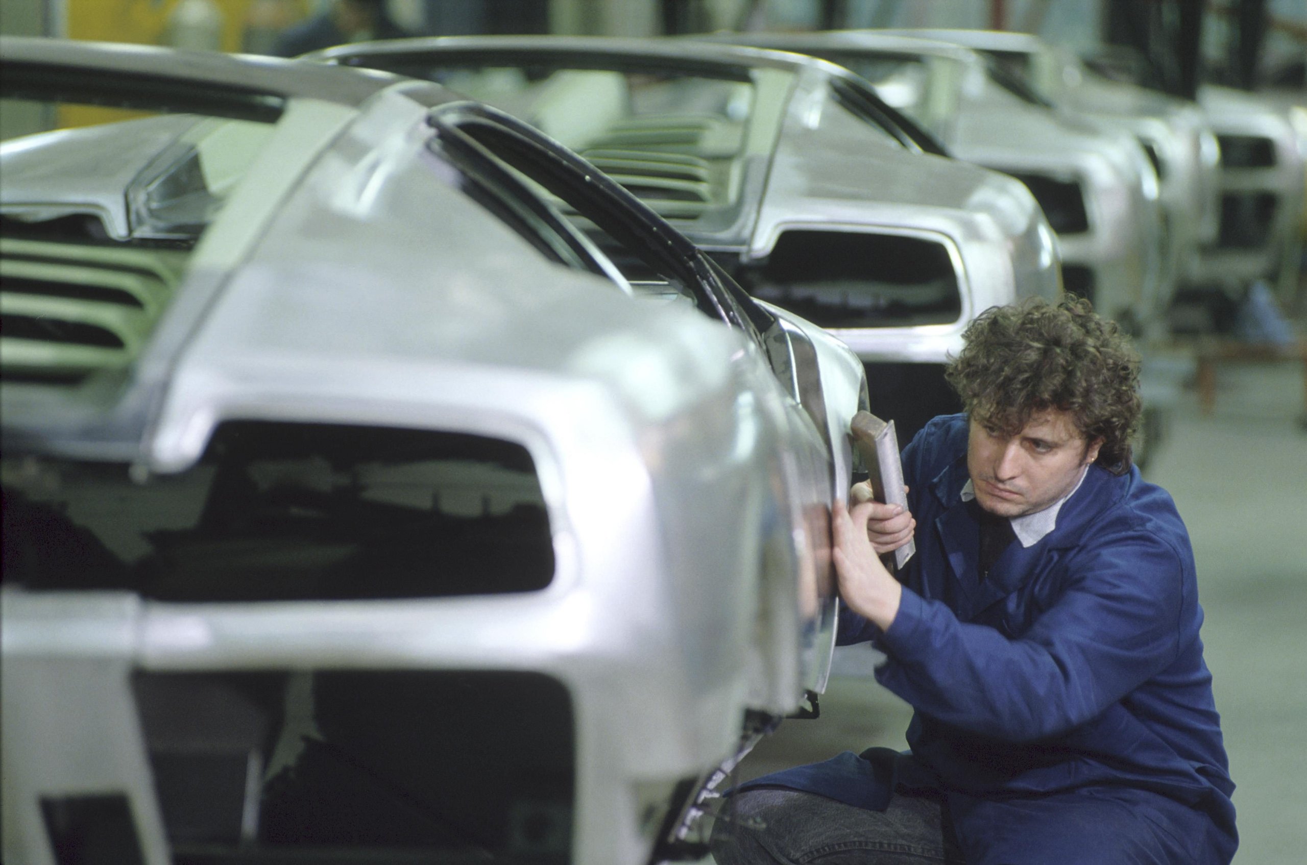 Worker meticulously sanding the body panel of a Lamborghini Diablo during the manufacturing process
