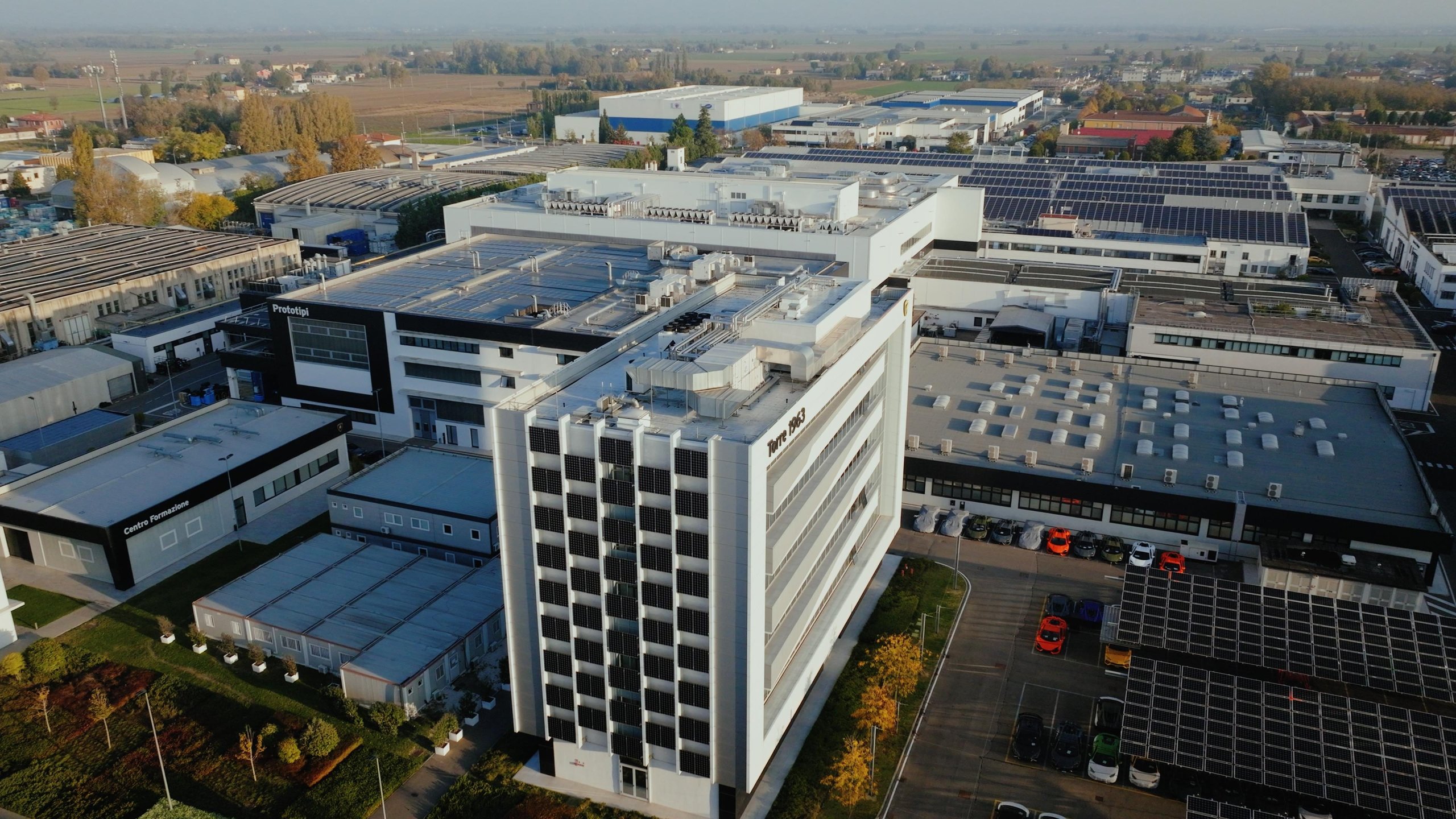 Aerial view of the lamborghini factory complex at sant'agata bolognese with solar panels on rooftops surrounded by greenery