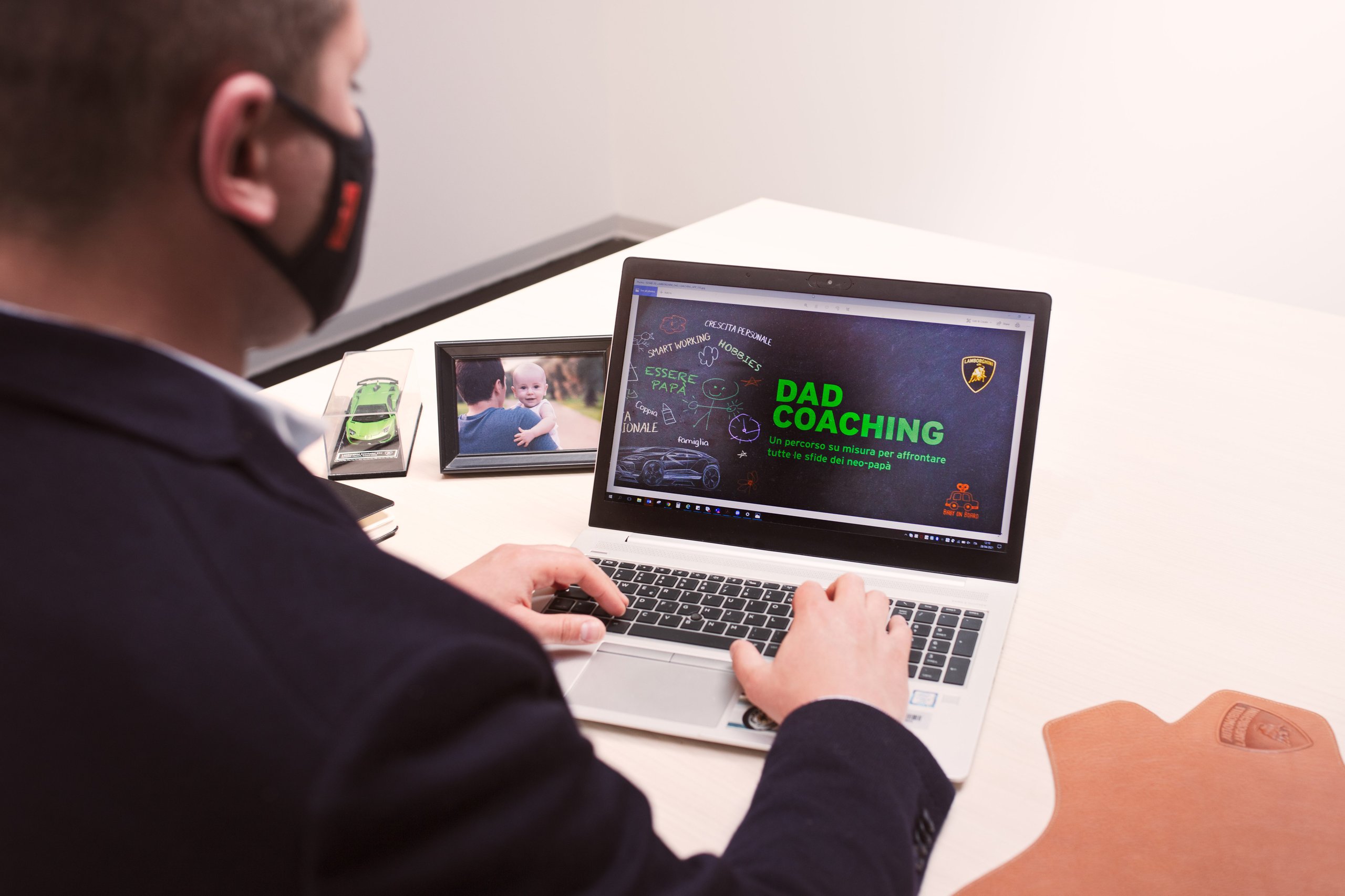 Inside Lamborghini'S Workforce Strategy: Why Dad Coaching And Reverse Mentoring Matter For Future Supercars 7 A lamborghini employee at a laptop displaying the dad coaching program with a baby photo and model lamborghini on the desk