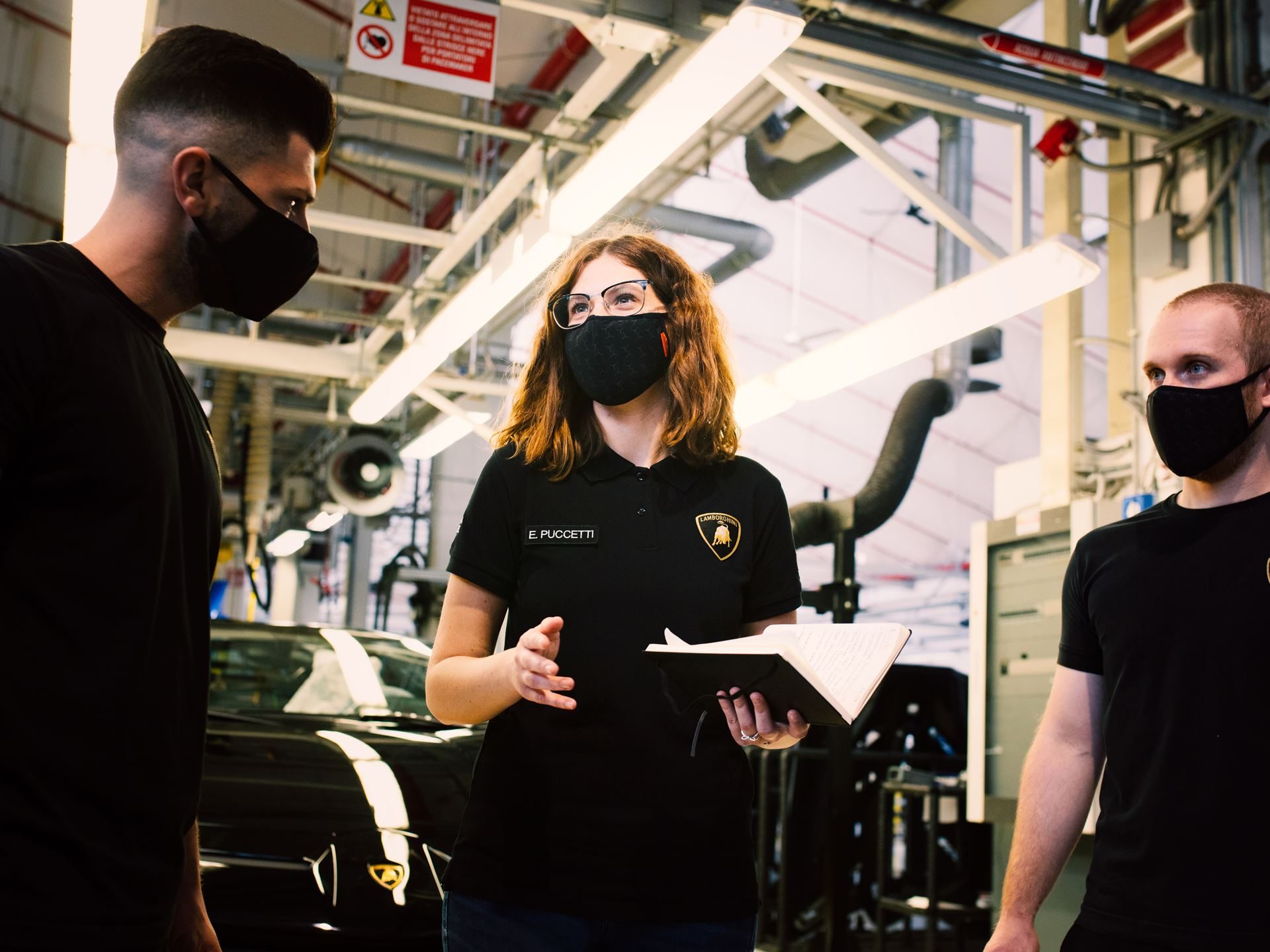 Inside Lamborghini'S Workforce Strategy: Why Dad Coaching And Reverse Mentoring Matter For Future Supercars 3 A female lamborghini employee discussing with two male colleagues in the factory with a huracan in the background
