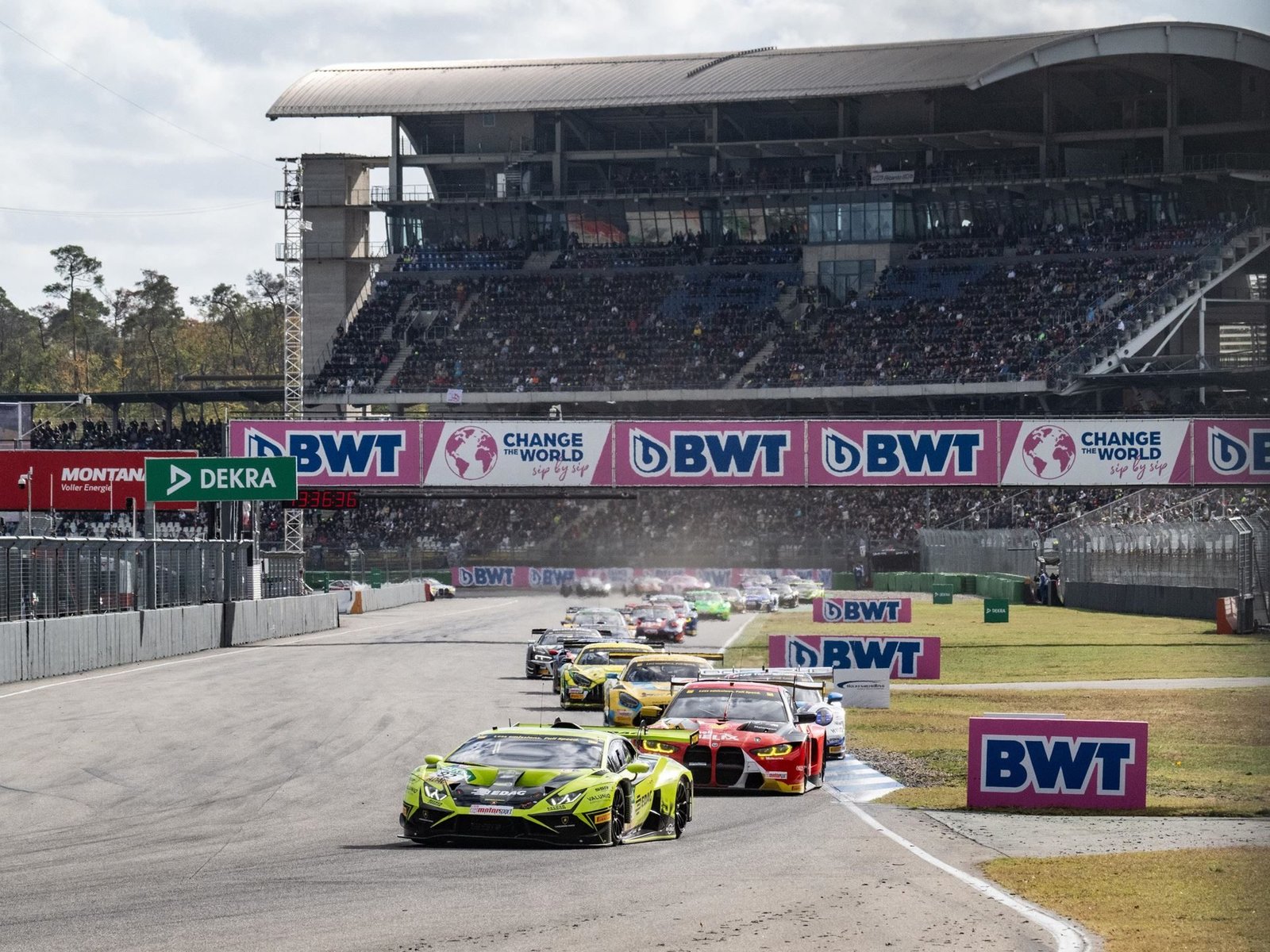 Lime green Lamborghini Huracán GT3 EVO2 leading a pack of DTM race cars on track with spectators in grandstands