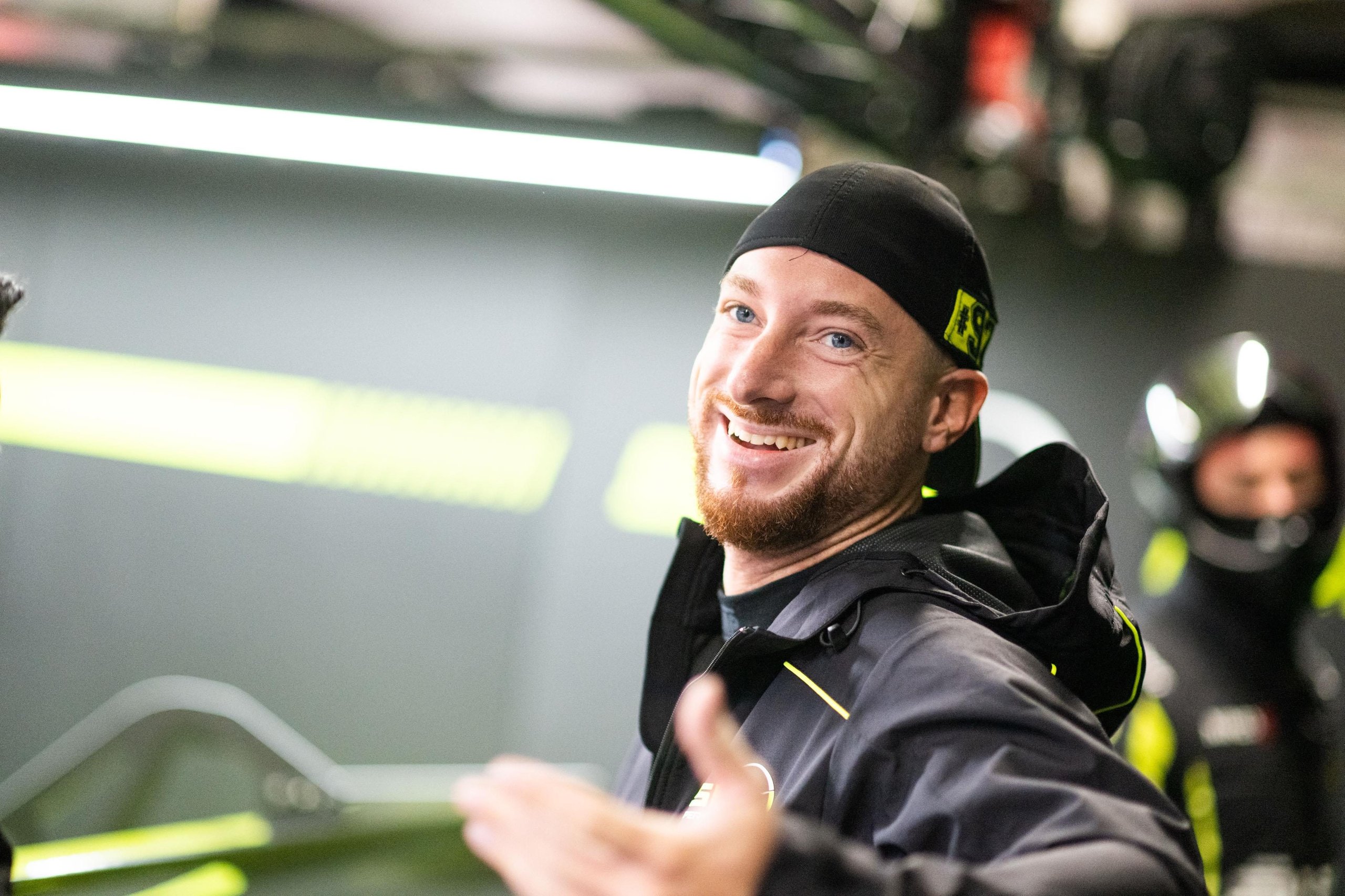 Five Wins, One Near-Miss Title: How The Huracán Gt3 Evo2 Delivered Lamborghini'S Best Dtm Season Yet 7 Smiling team member in black cap and black and yellow jacket in a dtm pit garage