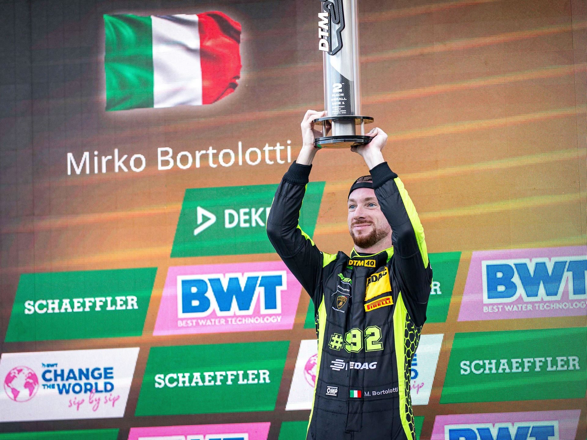 Engstler'S Three-Tenths Margin At Oschersleben Reveals Why The Huracán Gt3 Evo2 Still Bites 11 Mirko bortolotti on the dtm podium holding trophy with italian flag in background