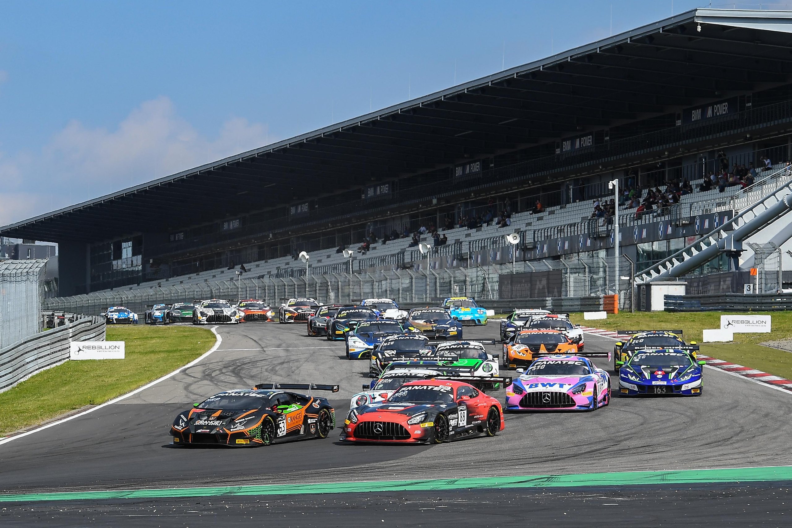 How Lamborghini'S 2021 Nürburgring Endurance Cup Win Built The Foundation For Its Gt3 Future 3 A pack of gt race cars including the lamborghini huracán gt3 evo navigating a wide turn at the nürburgring with grandstands visible