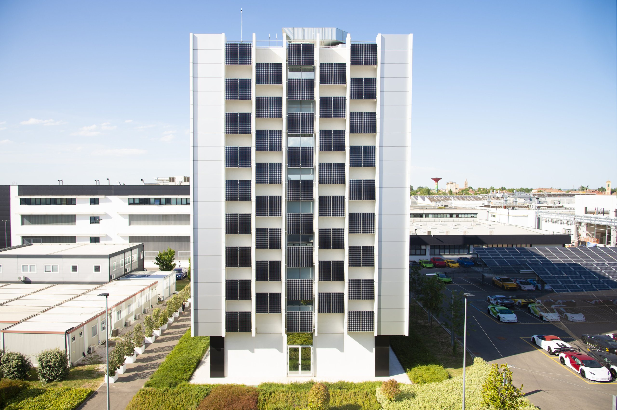 Bees, Biogas, And The Raging Bull: How Lamborghini'S Factory Sustainability Protects Its Performance Future 5 Frontal view of lamborghini's torre 1963 building with solar panel facade and colorful lamborghinis parked alongside