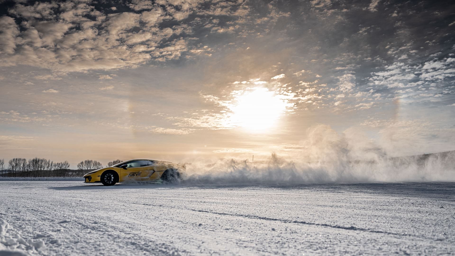 A yellow lamborghini huracán drifting on a snowy track with a dramatic cloud of snow
