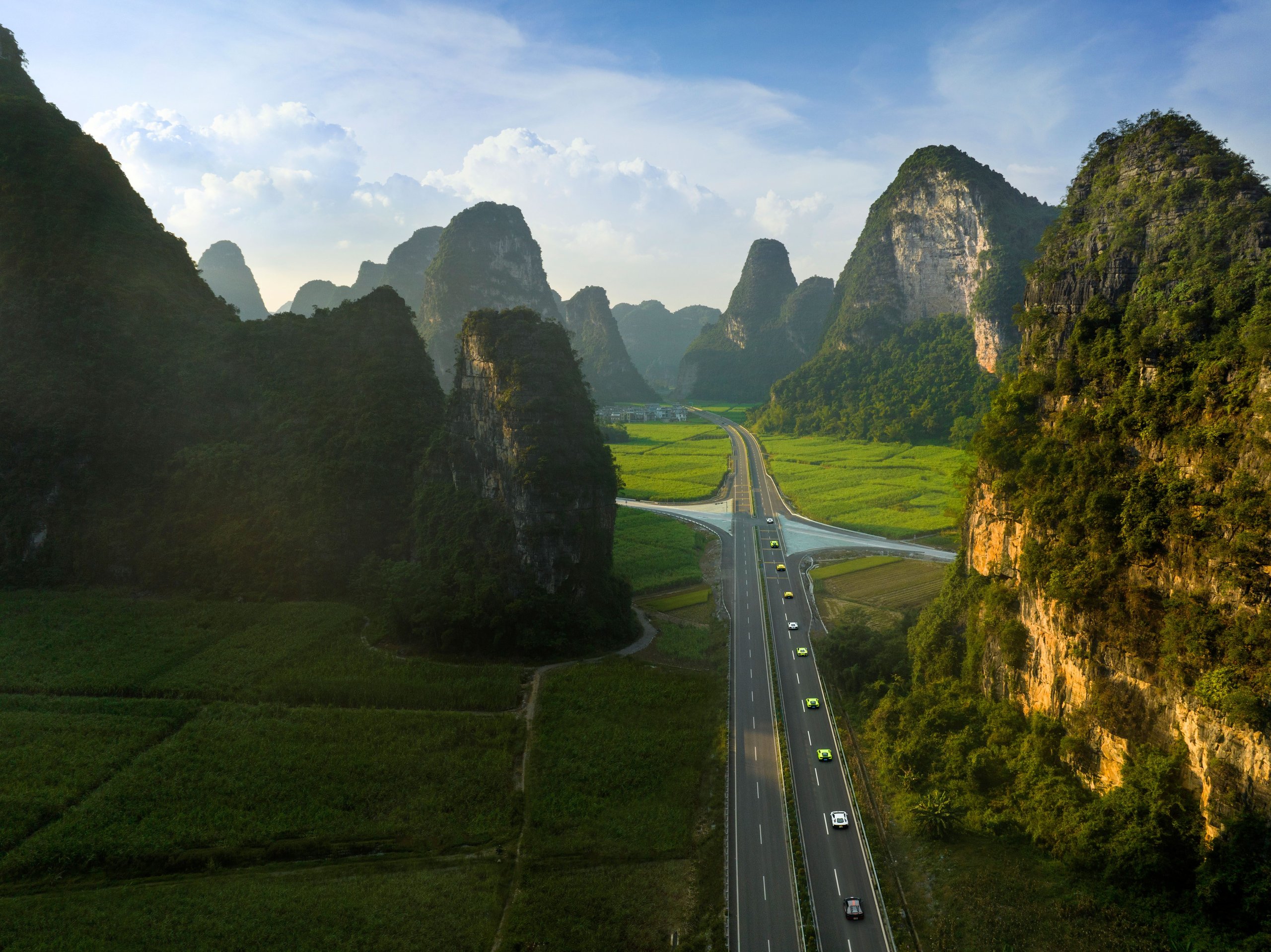 1,100 Kilometers Through Karst Country: How Lamborghini Turned Southern China Into A Rolling Showroom 3 Aerial view of a lamborghini convoy driving through karst mountain landscape and green fields in southern china