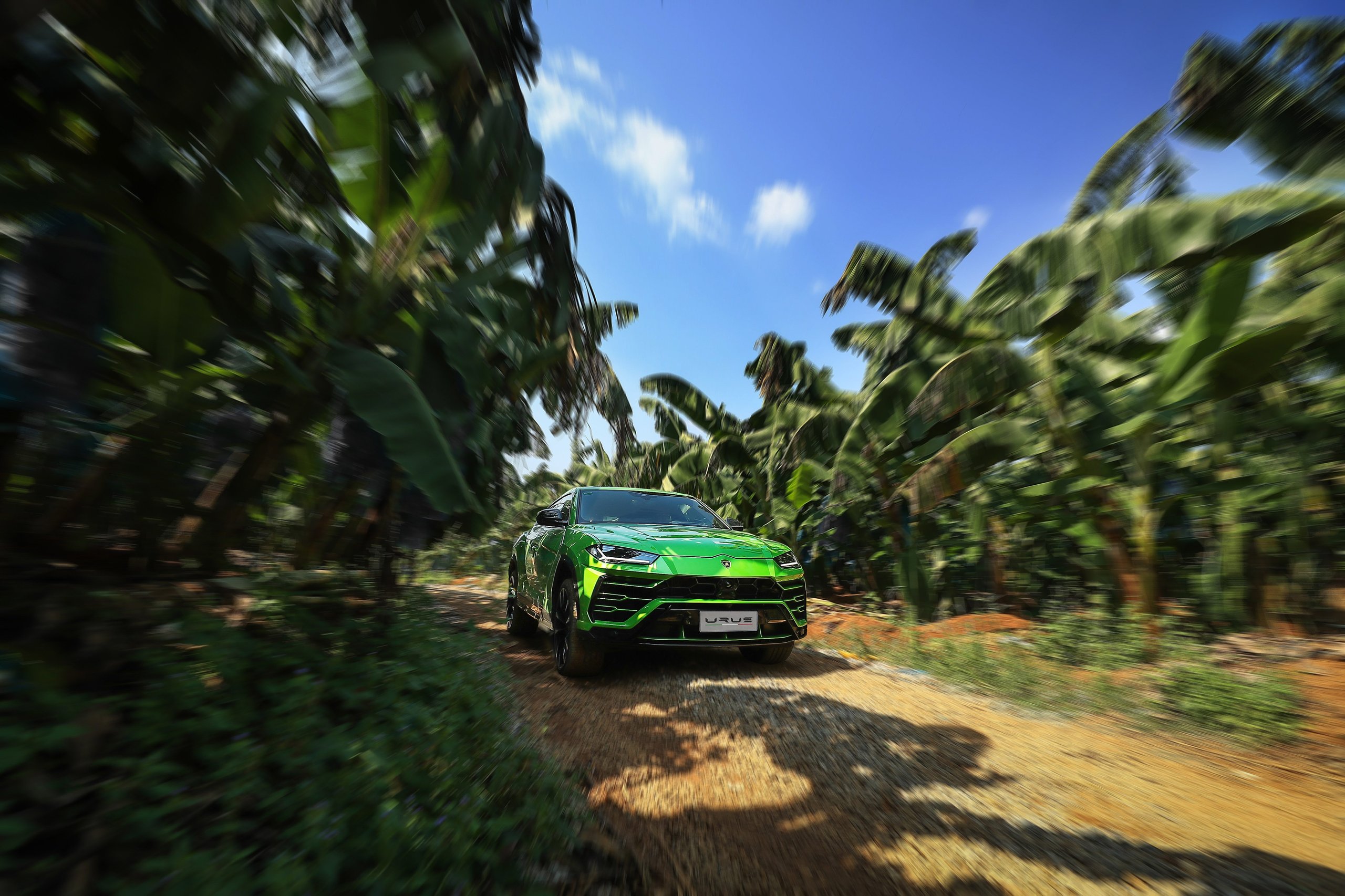 1,100 Kilometers Through Karst Country: How Lamborghini Turned Southern China Into A Rolling Showroom 7 Green lamborghini urus driving on a dirt road through lush tropical foliage with motion blur