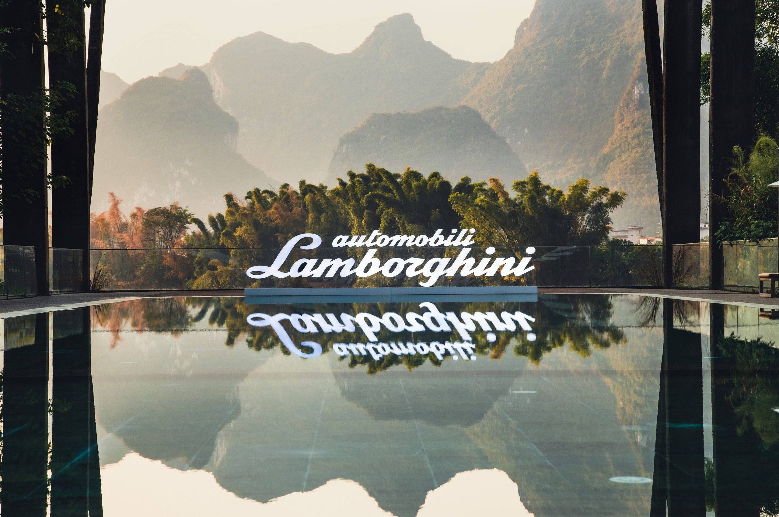 1,100 Kilometers Through Karst Country: How Lamborghini Turned Southern China Into A Rolling Showroom 5 Automobili lamborghini sign reflected in water with misty karst mountains and bamboo groves in the background