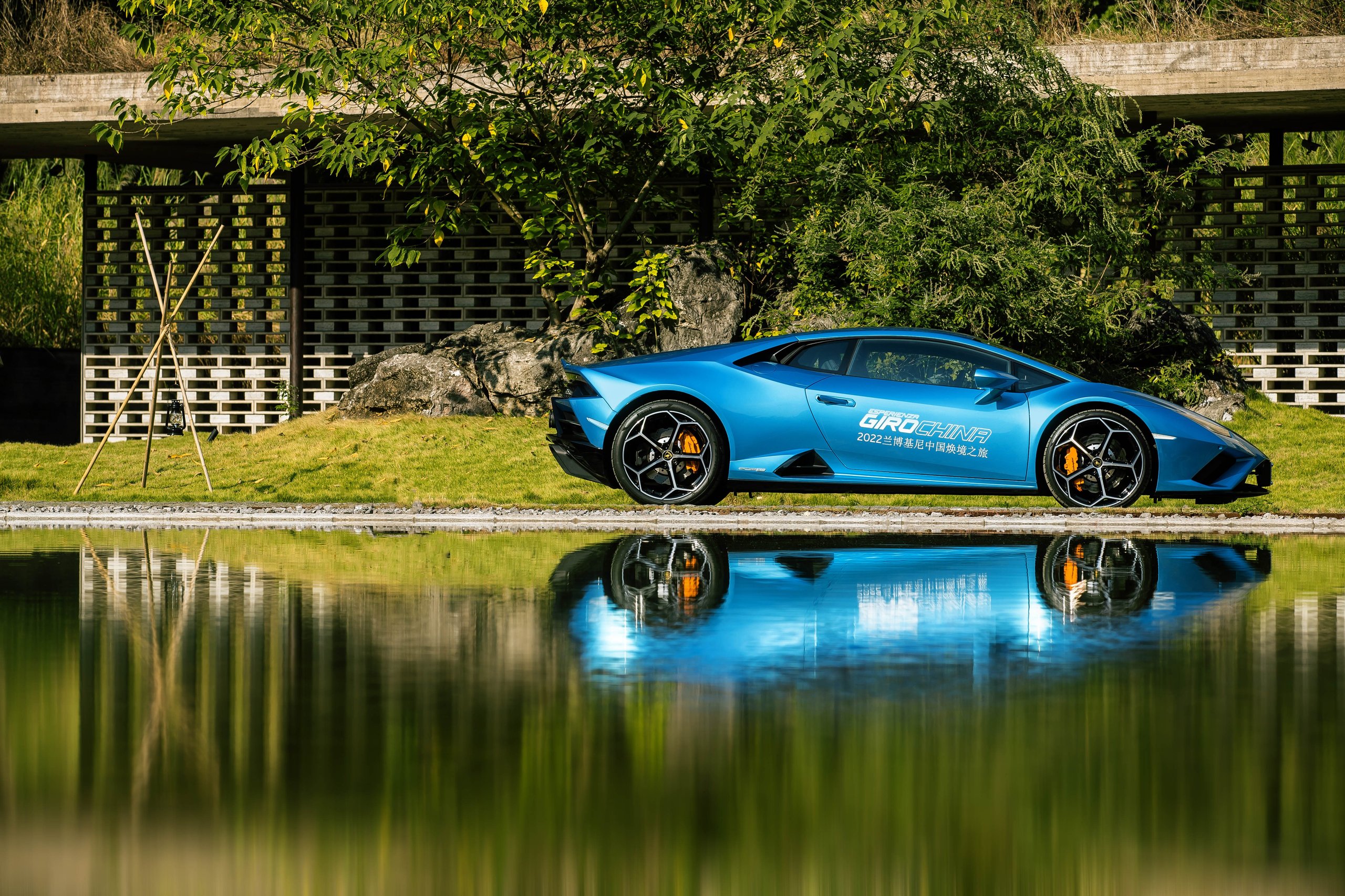 1,100 Kilometers Through Karst Country: How Lamborghini Turned Southern China Into A Rolling Showroom 9 Blue lamborghini huracán sto parked beside a reflective pool with modern architecture and lush greenery