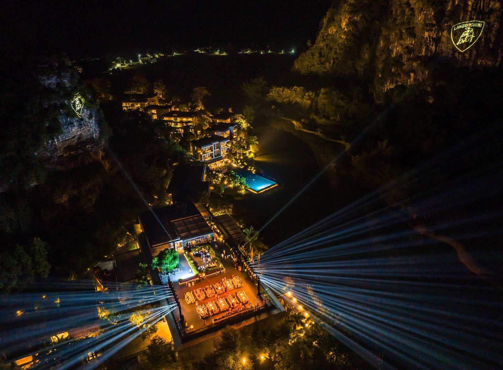 Aerial night view of Lamborghini Esperienza Giro China event with spotlights and the Lamborghini logo projected onto a karst cliff face