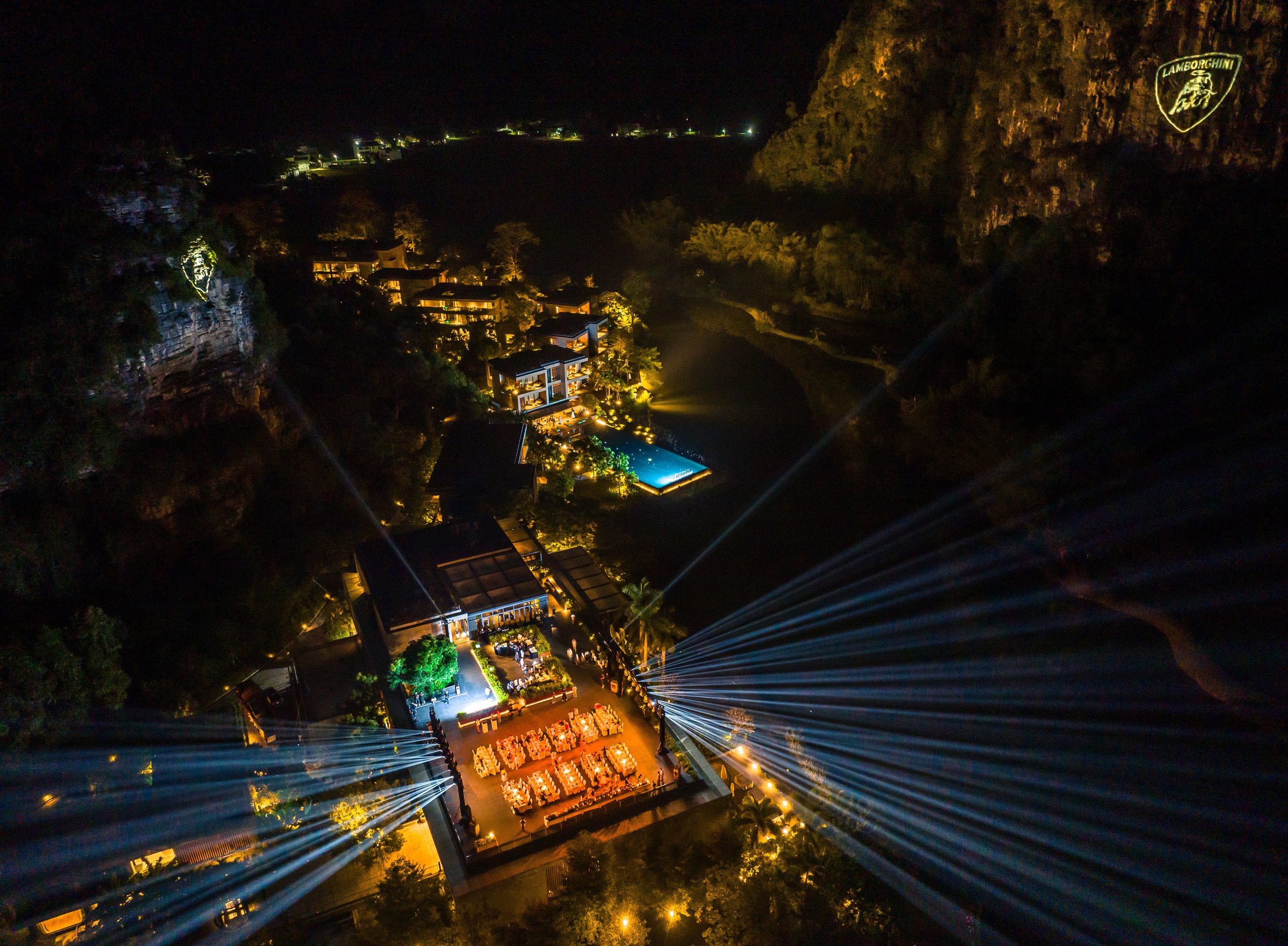 Aerial night view of lamborghini esperienza giro china event with spotlights and the lamborghini logo projected onto a karst cliff face