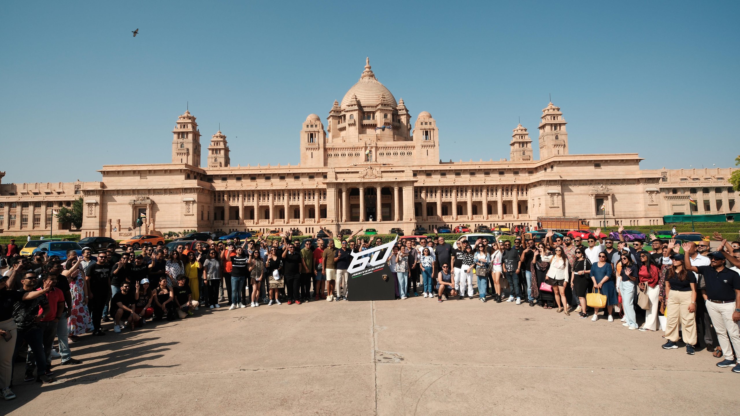 Lamborghini Esperienza Giro India 2023: A Royal 60Th Anniversary Celebration Across Rajasthan 3 Large group of lamborghini owners gathered in front of a grand rajasthani palace with a prominent 60th anniversary banner and colorful lamborghinis behind them